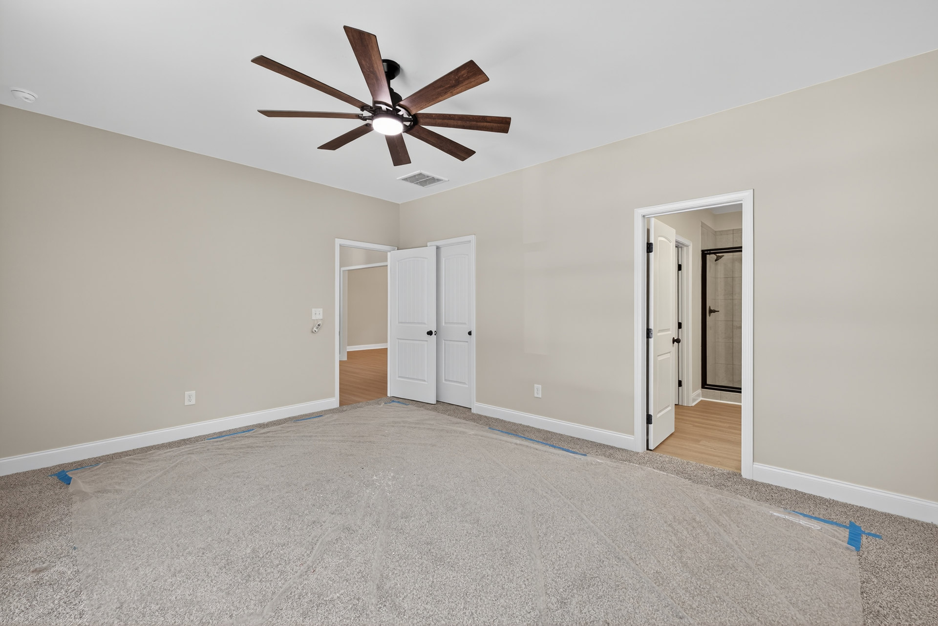 Carpeted room with white ceiling fan and light, white paneled door, neutral walls, and plaster ceiling