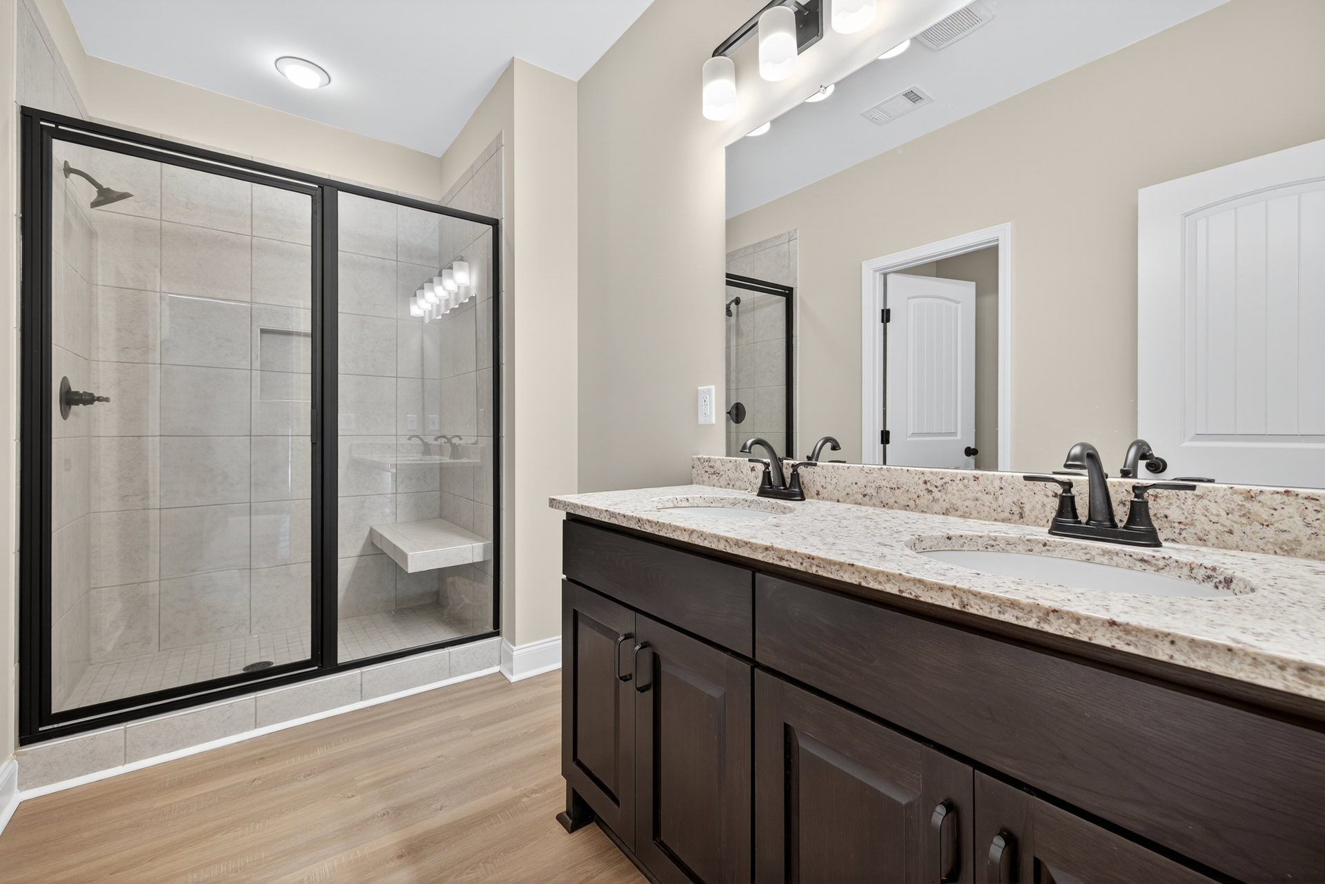 Bathroom with glass-enclosed shower, double sink vanity with chrome faucets, white tile walls, and modern cabinetry.
