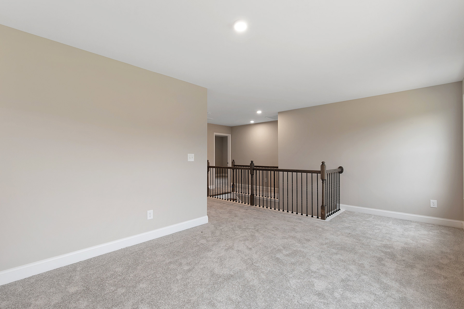 Carpeted floor with black metal railing, white walls and ceiling, close-up view of a door, bright natural light illuminating the space