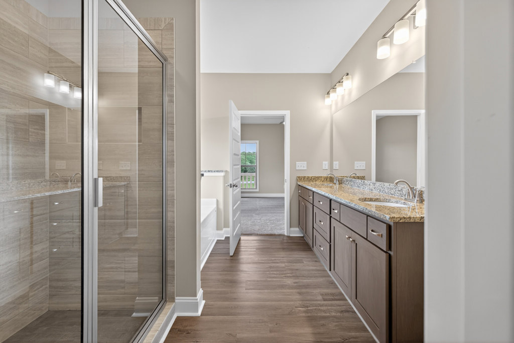 Bathroom featuring glass-enclosed shower, double vanity with white countertops, light tile flooring, and modern chrome fixtures
