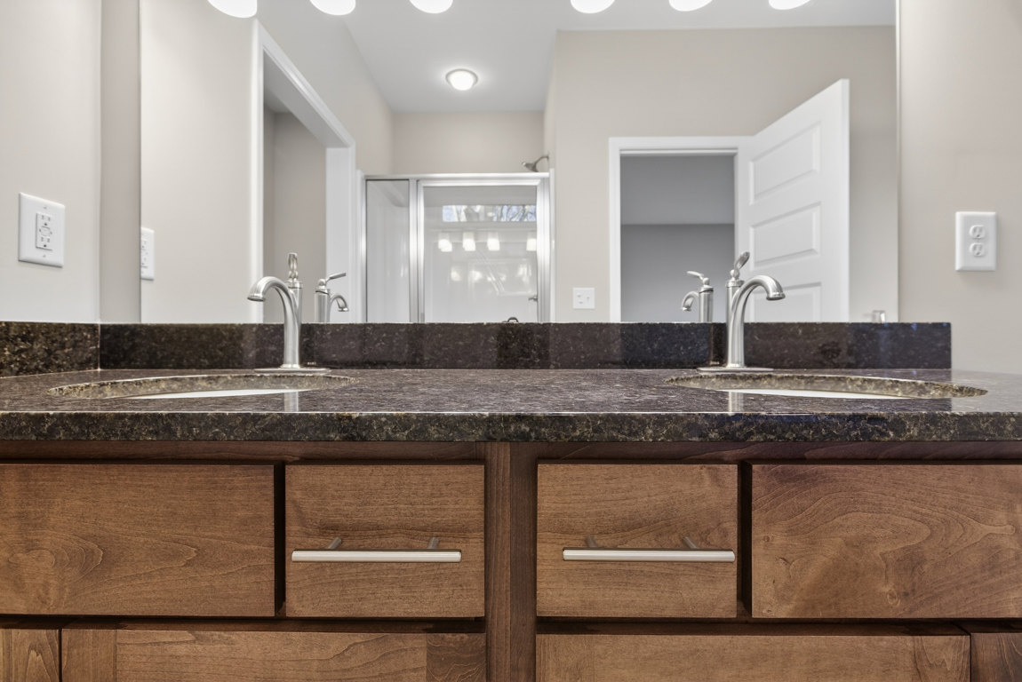 Double vanity bathroom with white quartz countertop, chrome faucets, light gray tile backsplash, and shaker-style cabinetry with brushed nickel hardware