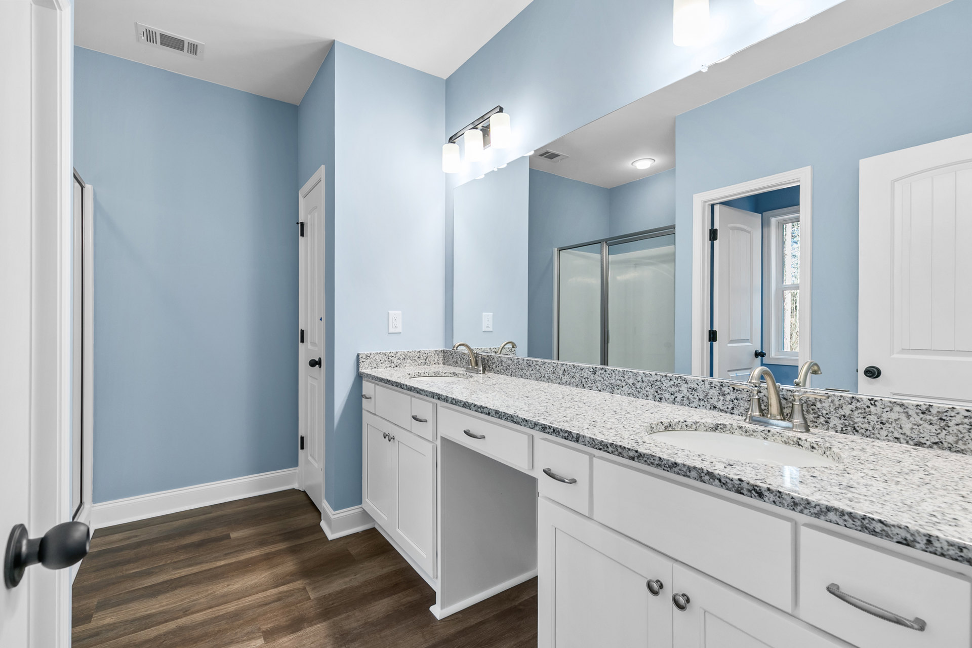 Bathroom featuring a marble countertop with undermount sink, glass-enclosed shower with tile walls, white cabinetry, chrome fixtures, and neutral tile flooring