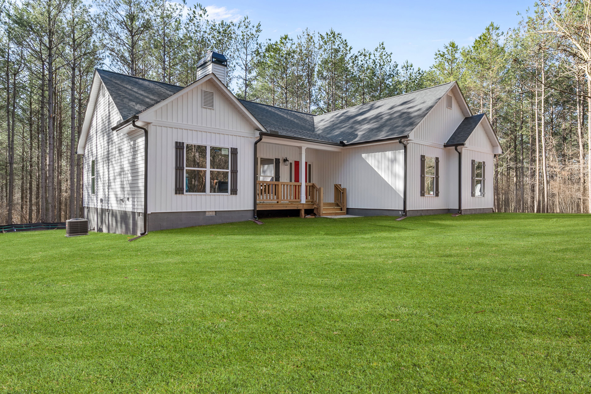 White siding house with covered porch, wooden railing, white-framed windows, and green grass lawn