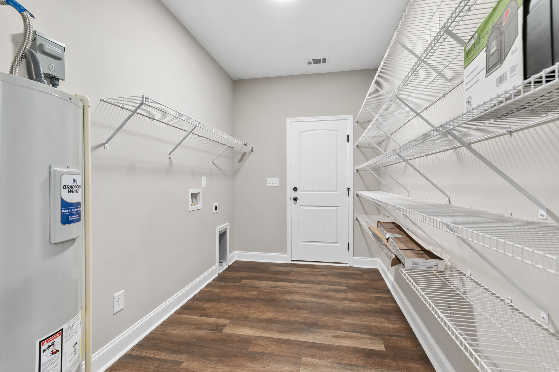 White built-in shelves beside a white door with black hardware, wood flooring, and white plaster walls in a residential interior.