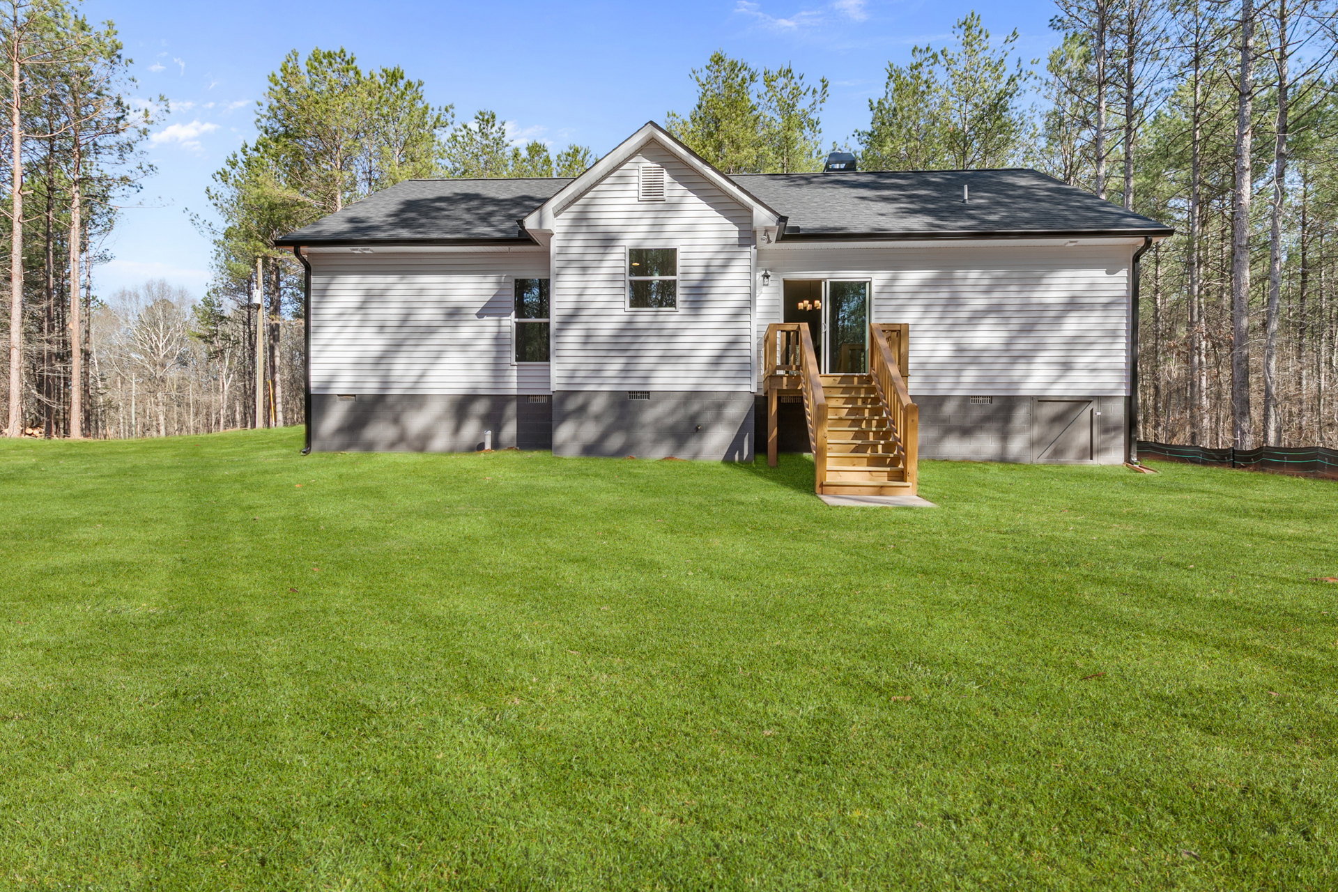 Two-story house with white-framed windows, wooden exterior staircase, and green grass lawn; yellow frisbee visible in front yard.