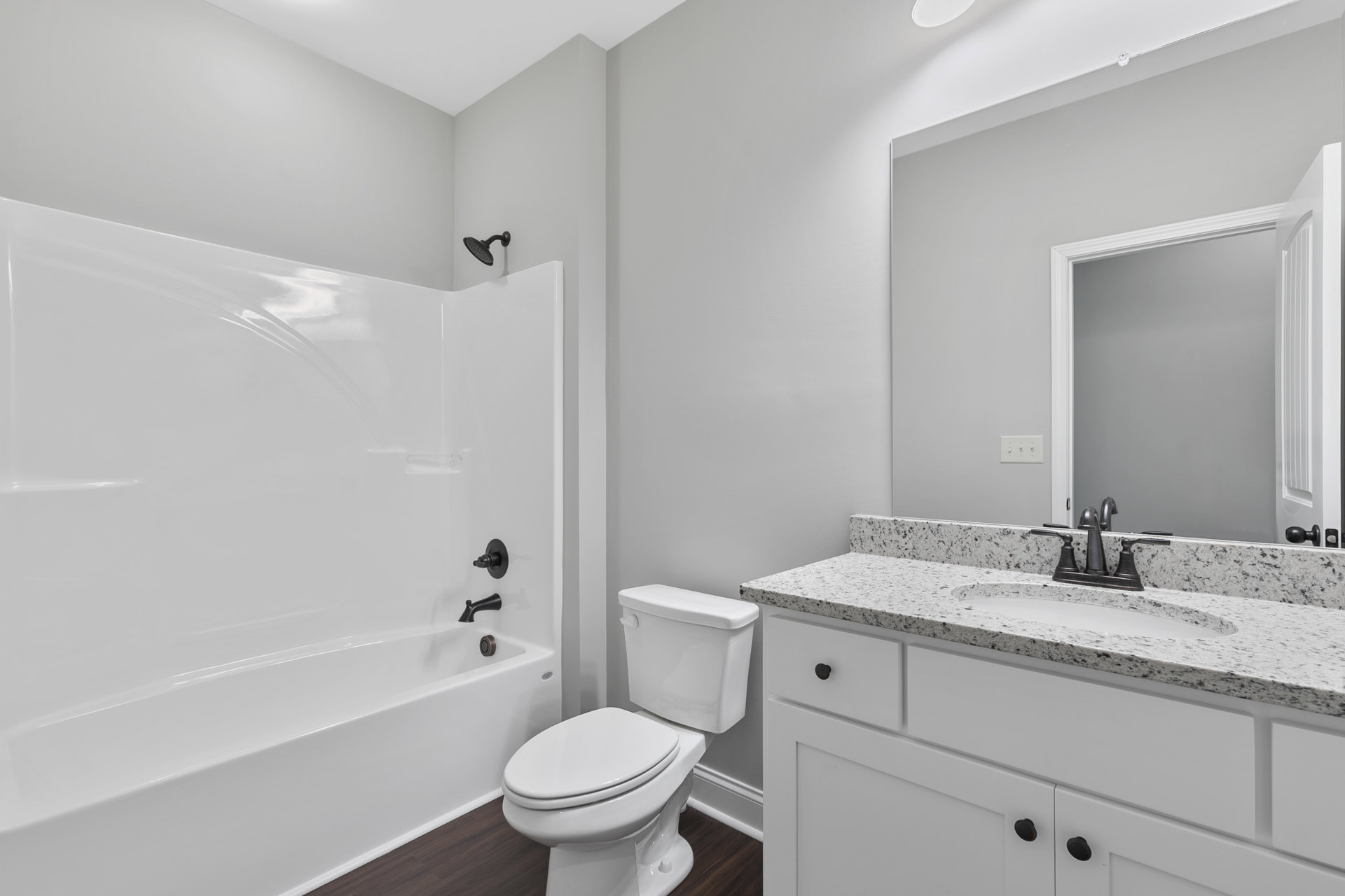 Bathroom with white toilet, rectangular sink on vanity, wall-mounted mirror, light gray tile flooring, and white walls