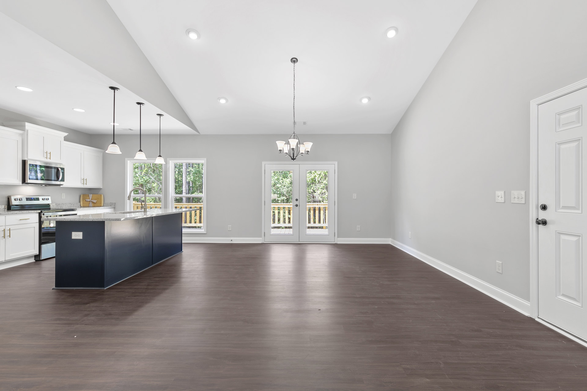 Spacious kitchen with wood flooring, white cabinetry, granite island countertop, glass-paneled double doors, built-in microwave, and recessed lighting