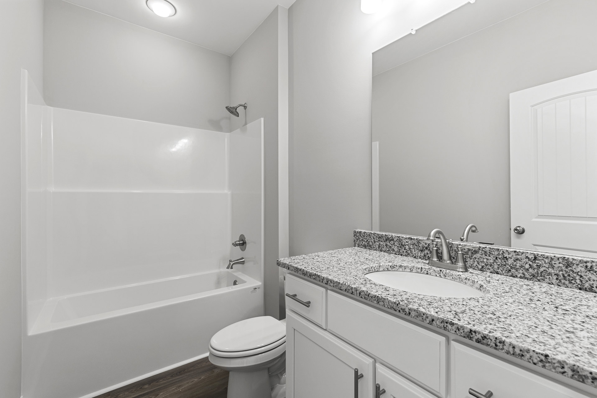 Bathroom with white toilet, freestanding bathtub, tile walls, built-in sink and cabinet, chrome faucet, and wall-mounted shower head