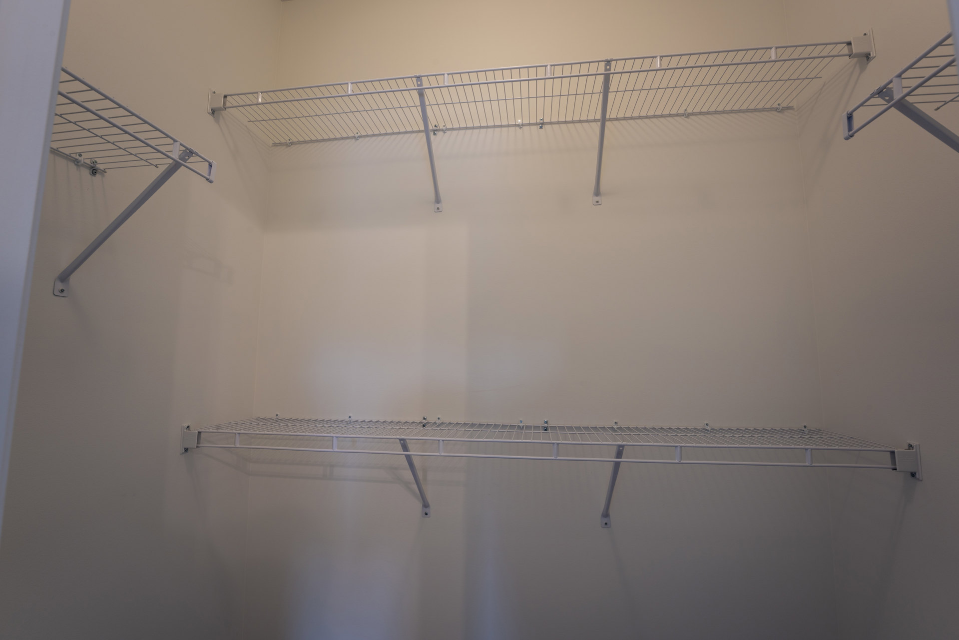 White metal shelving units with parallel rods and brackets mounted on a wall in a residential room.