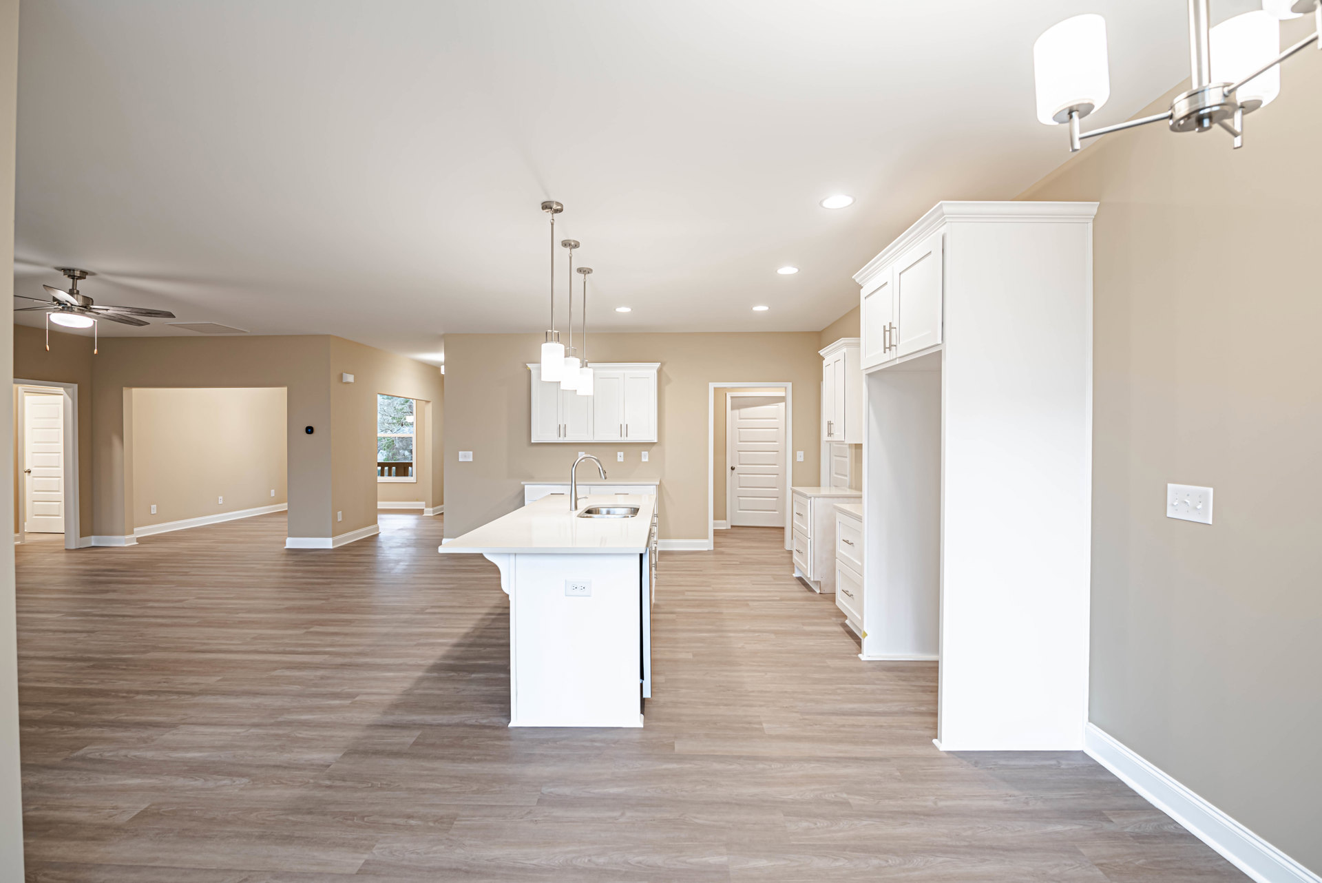 Open kitchen and dining area featuring a white kitchen island with built-in sink and chrome faucet, light switch on adjacent wall, white door with round handle, tile flooring