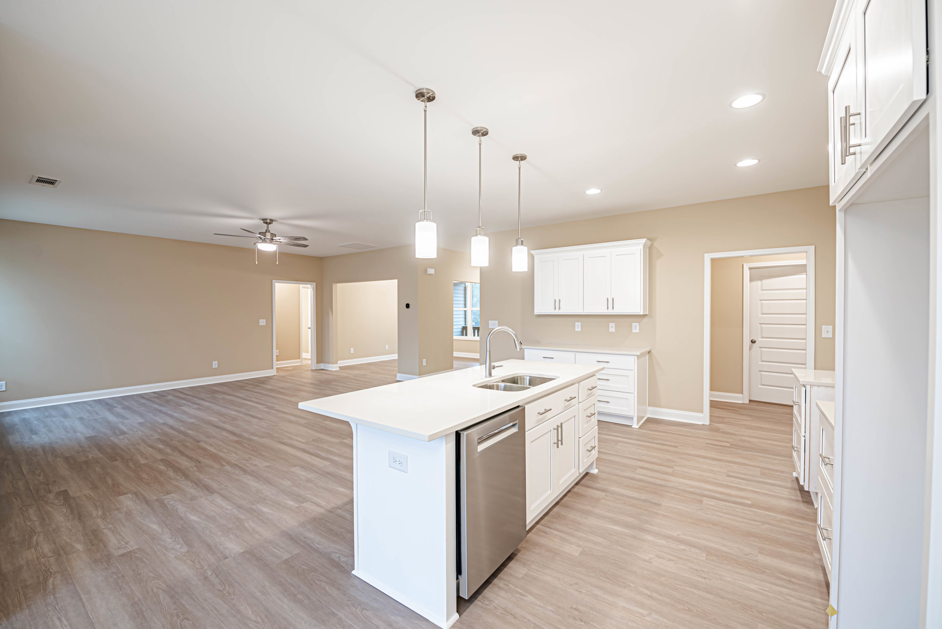 White kitchen with shaker cabinets, silver handles, stainless steel dishwasher, undermount sink, quartz countertops, and a person opening a stainless steel refrigerator near a