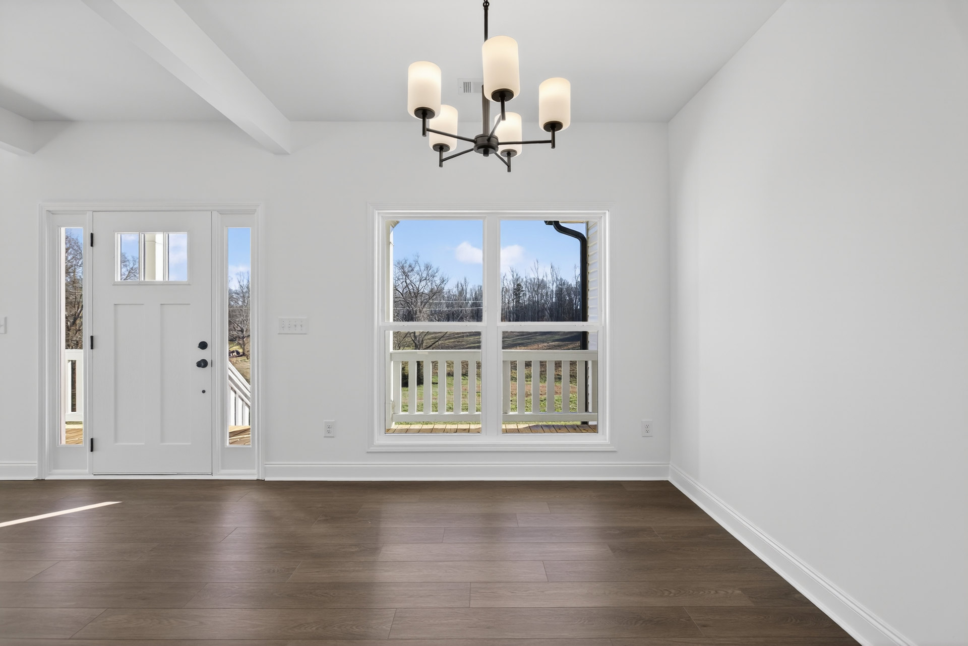 Wood floor with tile pattern, white walls, large window and door opening to a white porch overlooking trees, ceiling chandelier with white lamps, close-up of white lamp.