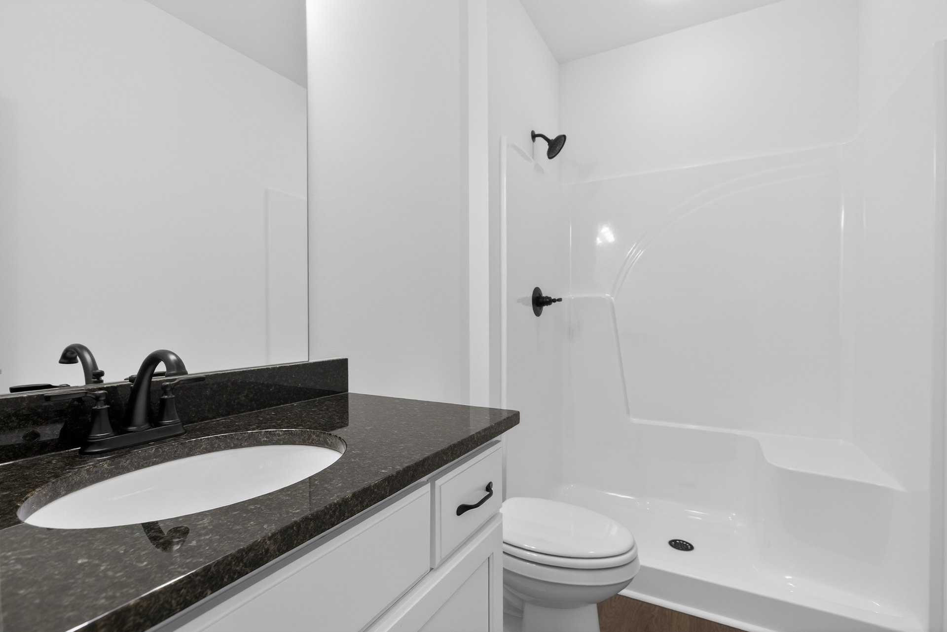 Bathroom with white tile walls, black shower head, white sink with black faucet, and closed white toilet.