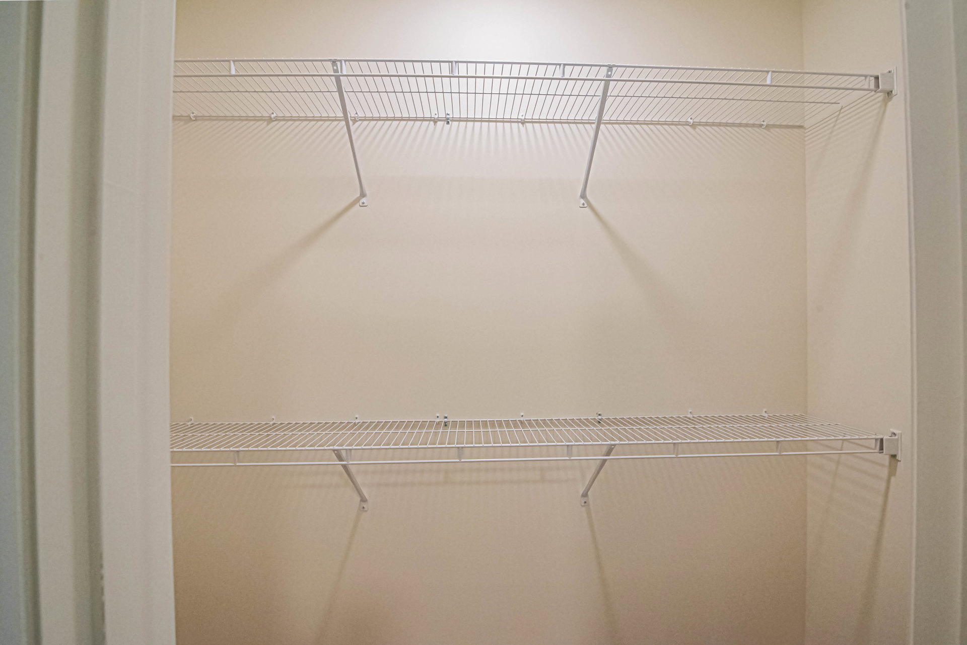 White metal shelf with hooks mounted on a wall in a residential interior