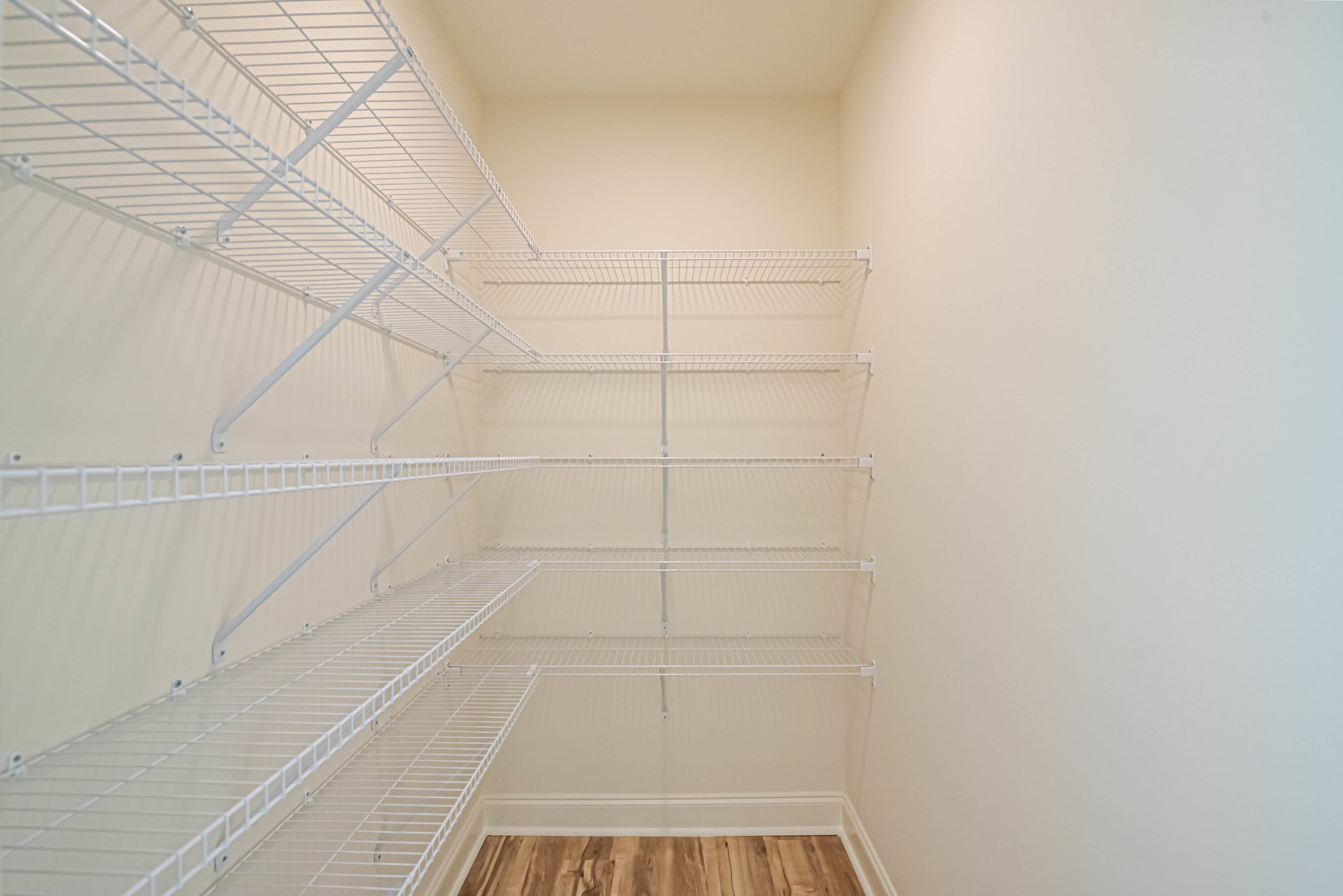Empty closet with white built-in shelves and wood flooring