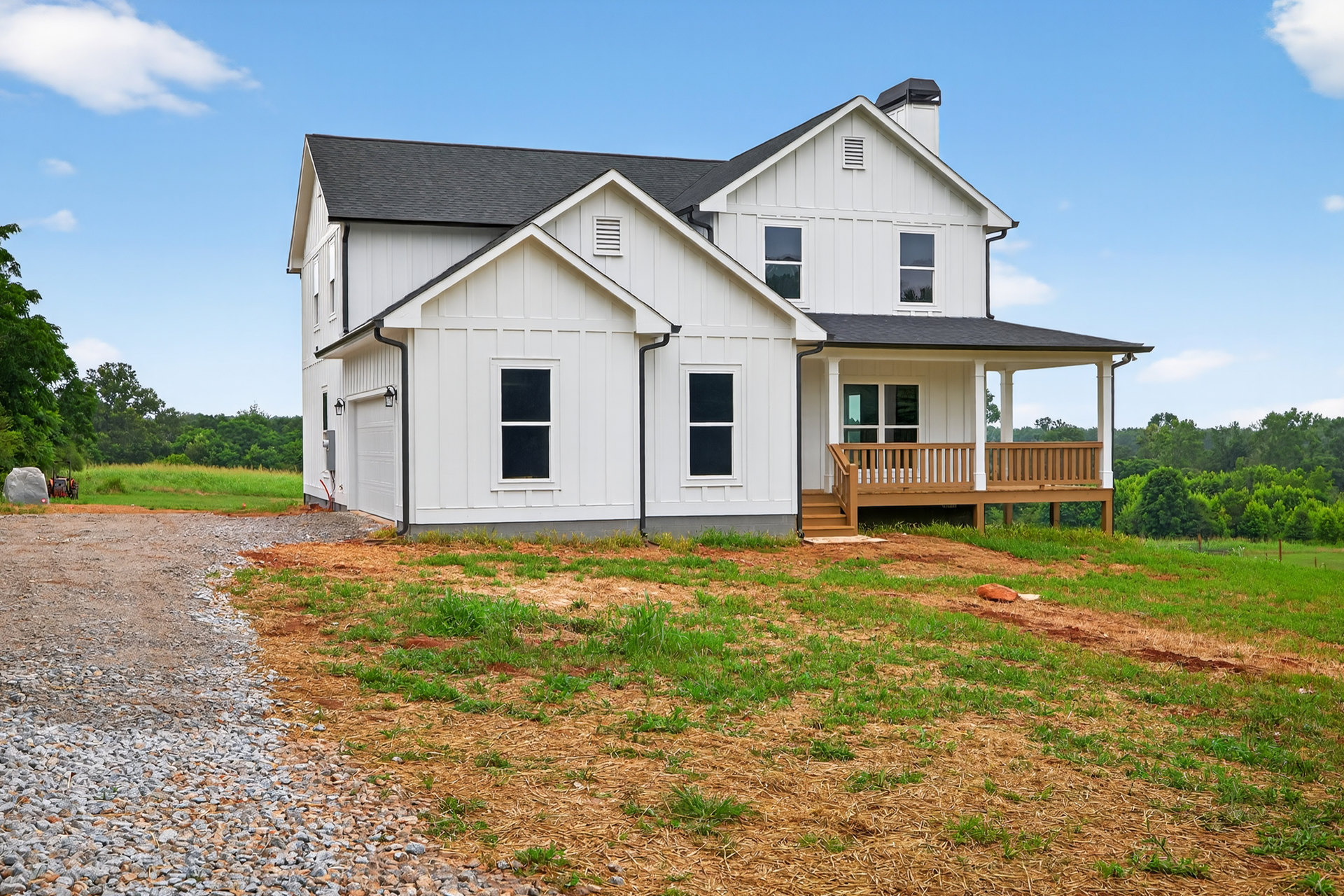 White siding house with covered porch, white columns, gravel walkway, grassy lawn, and white-framed windows
