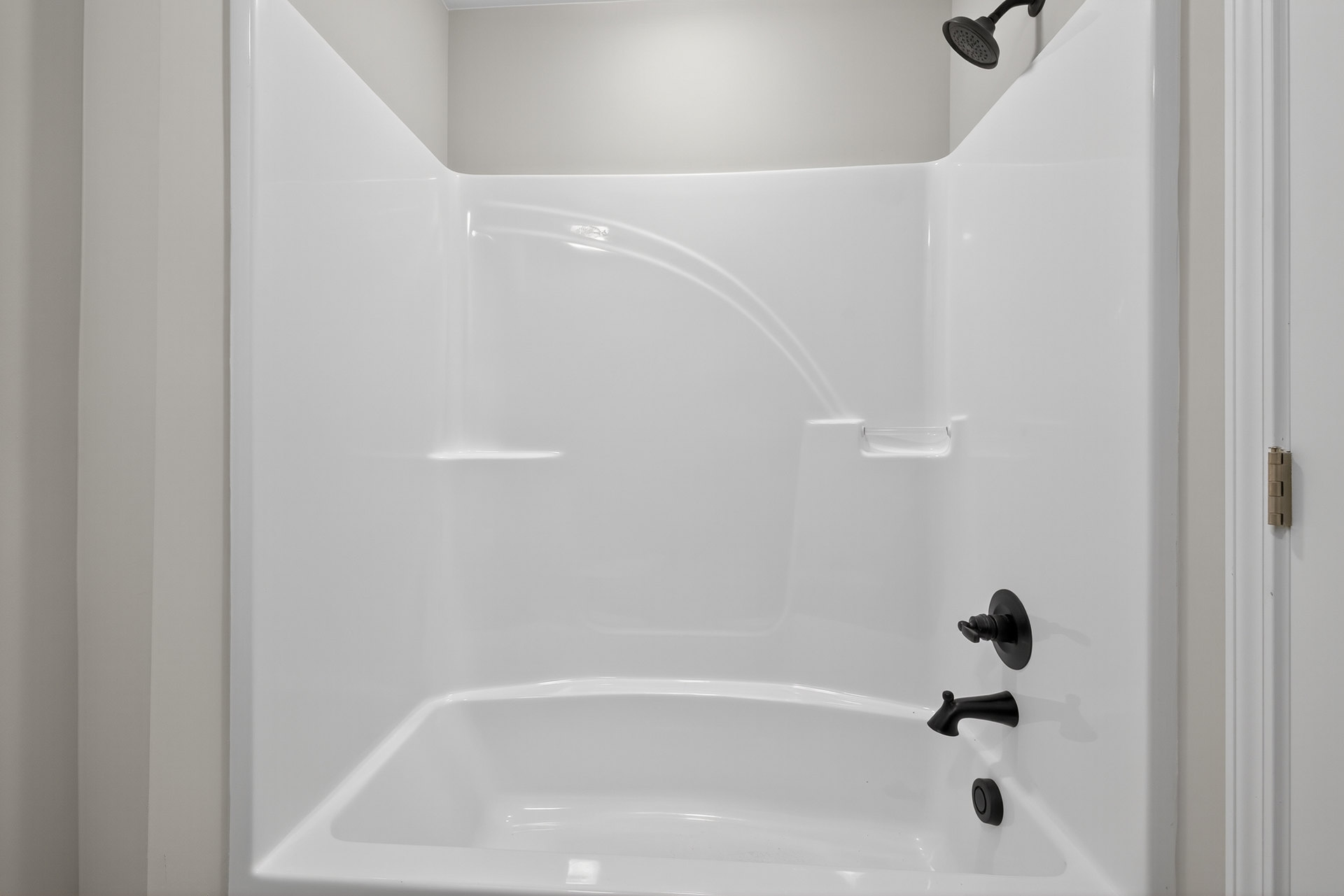 Freestanding white bathtub with matte black faucet and fixtures against a light-colored bathroom wall