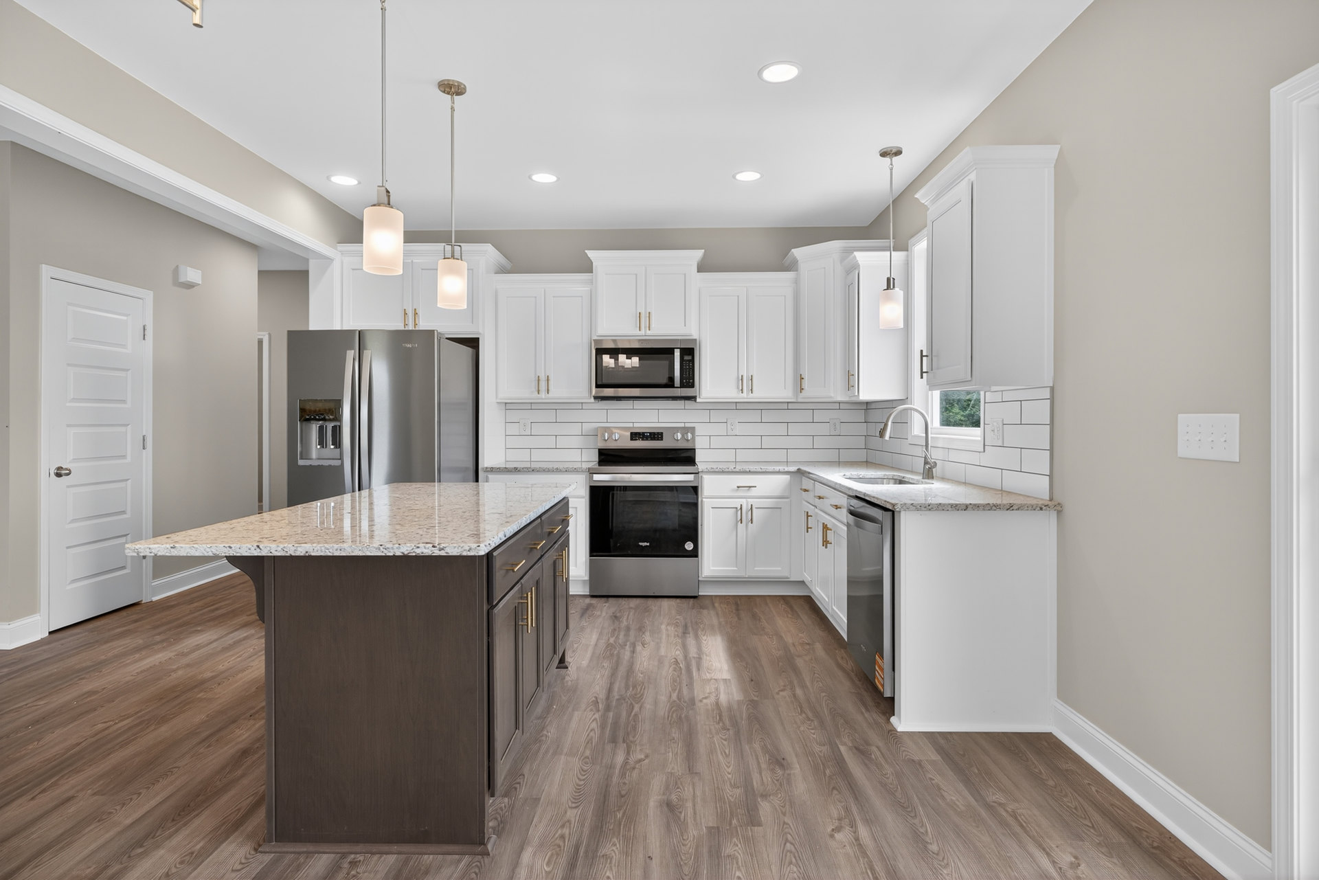 White kitchen with marble island, stainless steel oven and microwave, open refrigerator, white cabinetry, granite countertops, and silver door handle