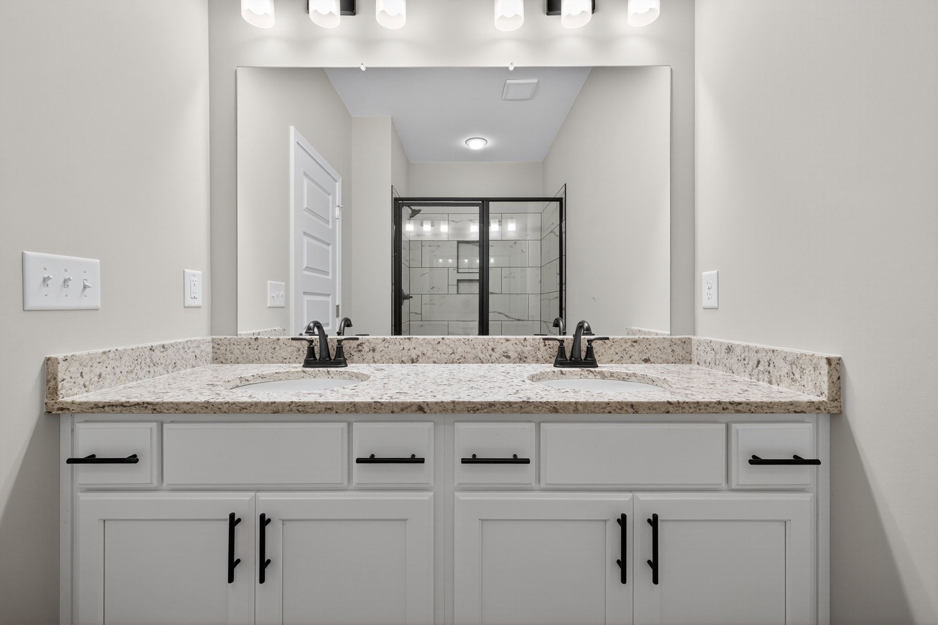 Bathroom with white cabinets, marble countertop, glass shower enclosure, and tile flooring