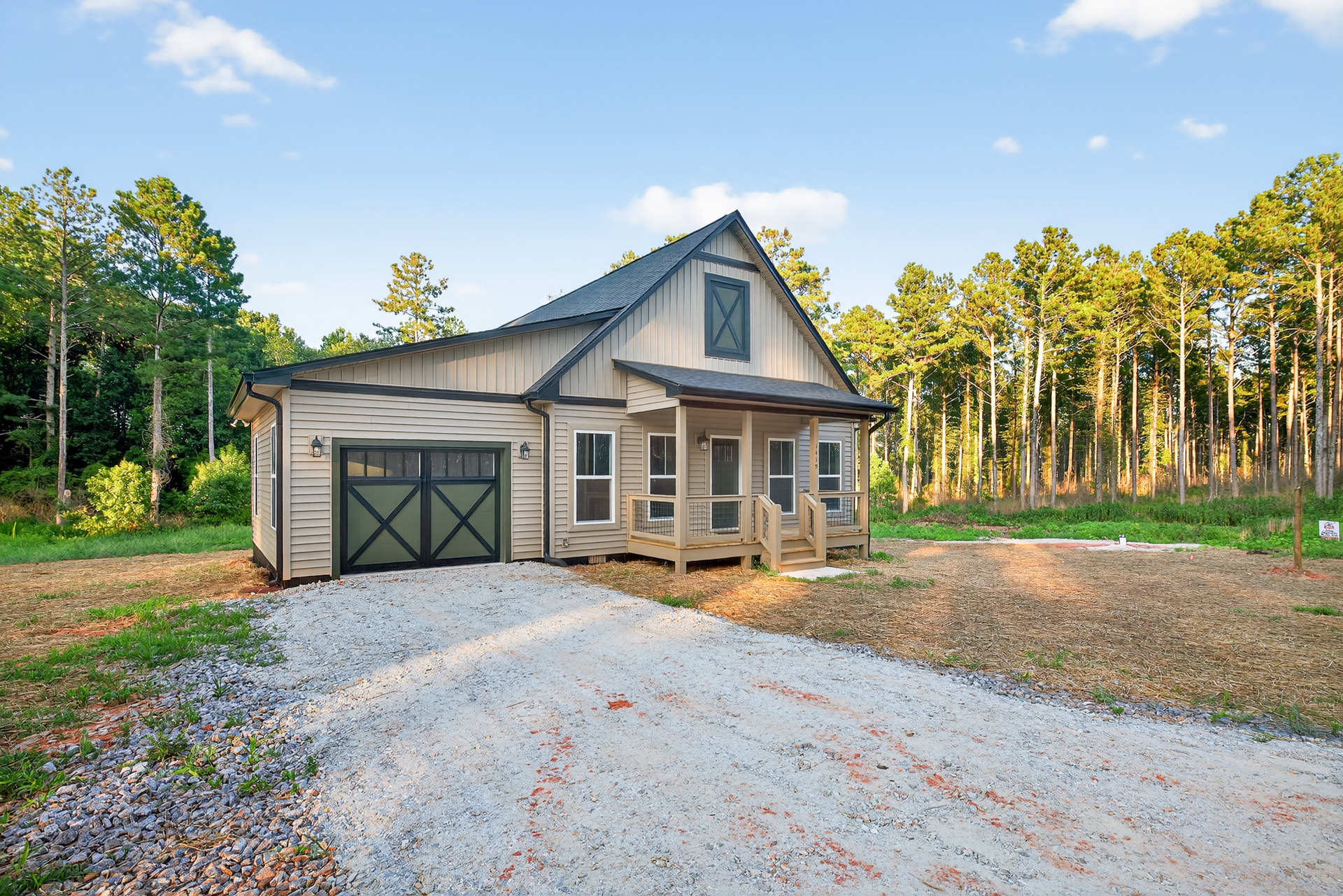 Two-story house with green garage door and black trim, white-framed windows, concrete driveway bordered by grass, mature trees in the background
