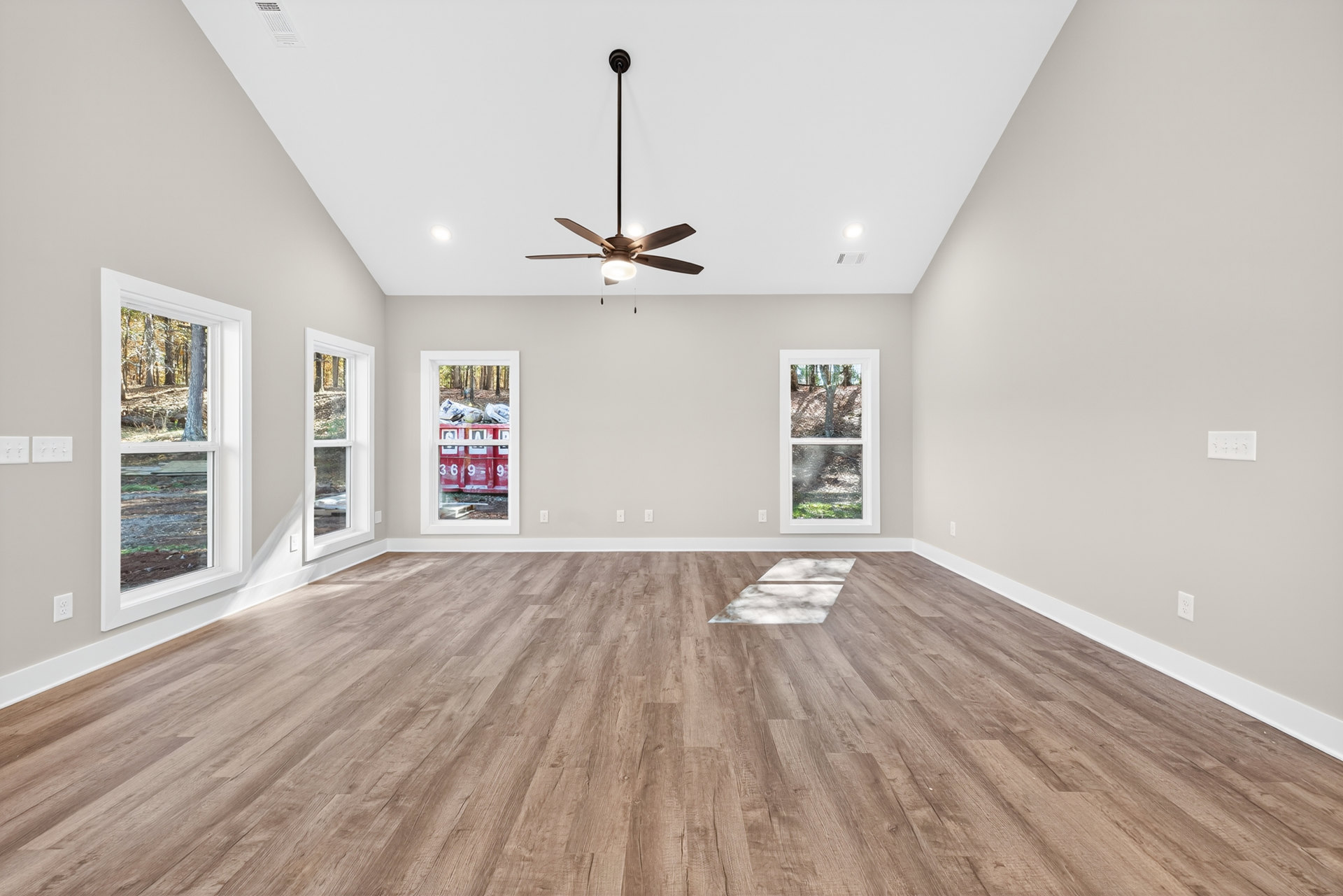Ceiling fan with light fixture, wood floor featuring white square marble tiles, two windows including one with broken glass and a red box displaying white numbers, plaster walls