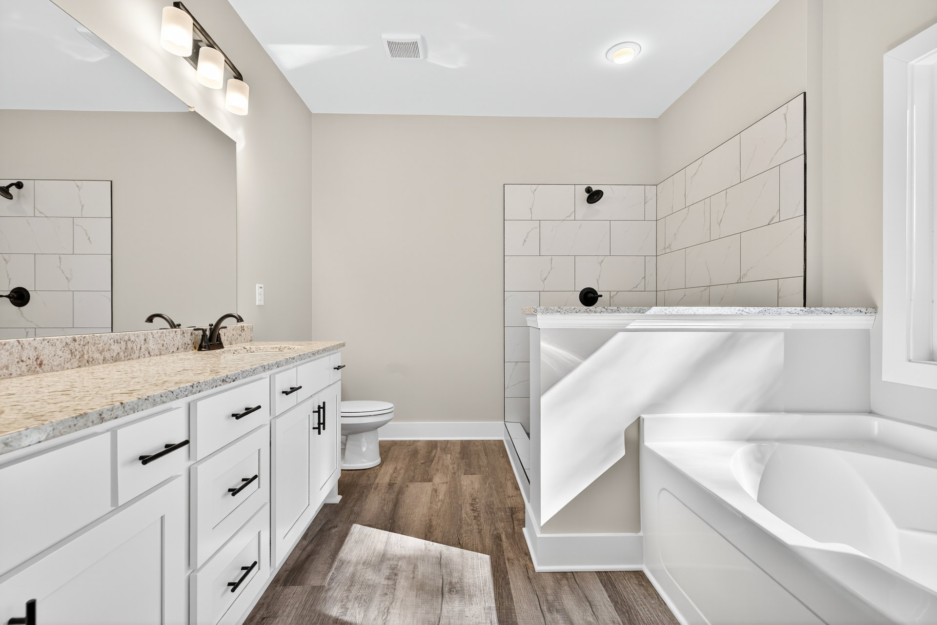 Bathroom with white shaker cabinets, white freestanding bathtub, light tile flooring, and chrome plumbing fixtures