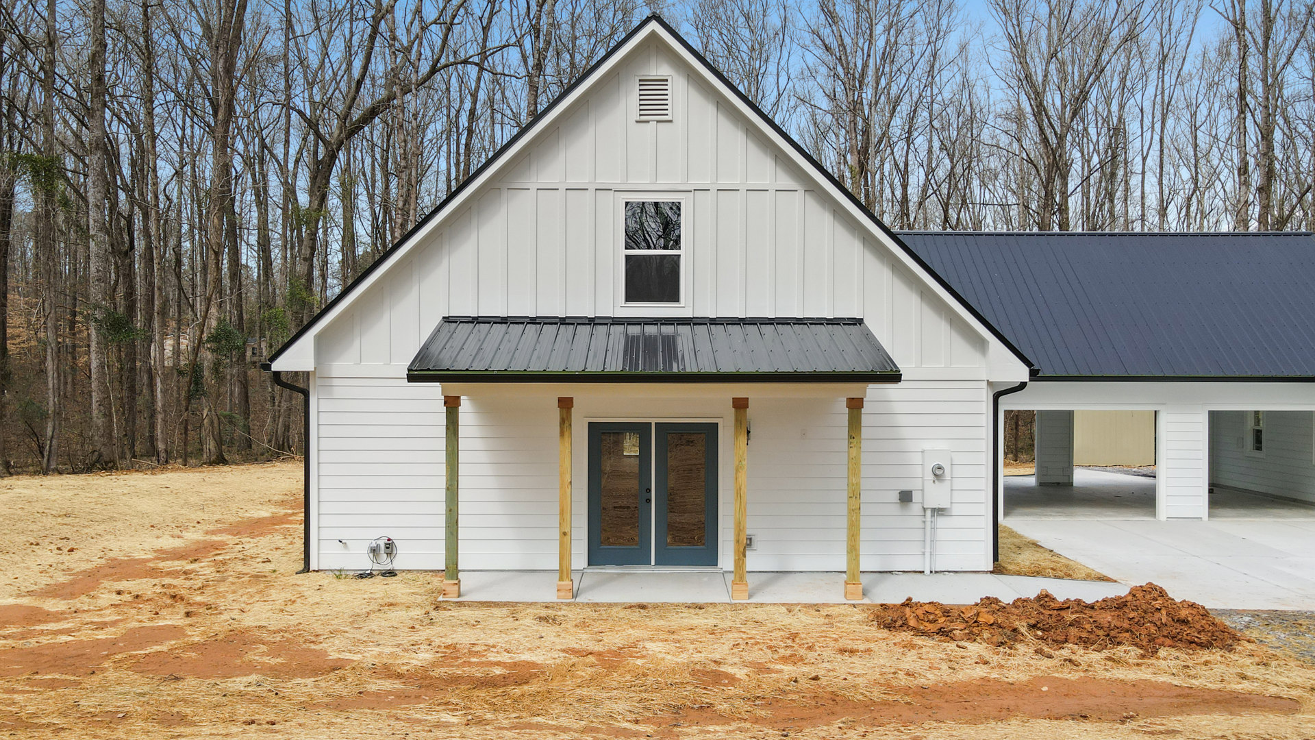 White siding house with black shingle roof, double glass-paneled front doors, large window reflecting tree, white vent above entry, landscaped front yard