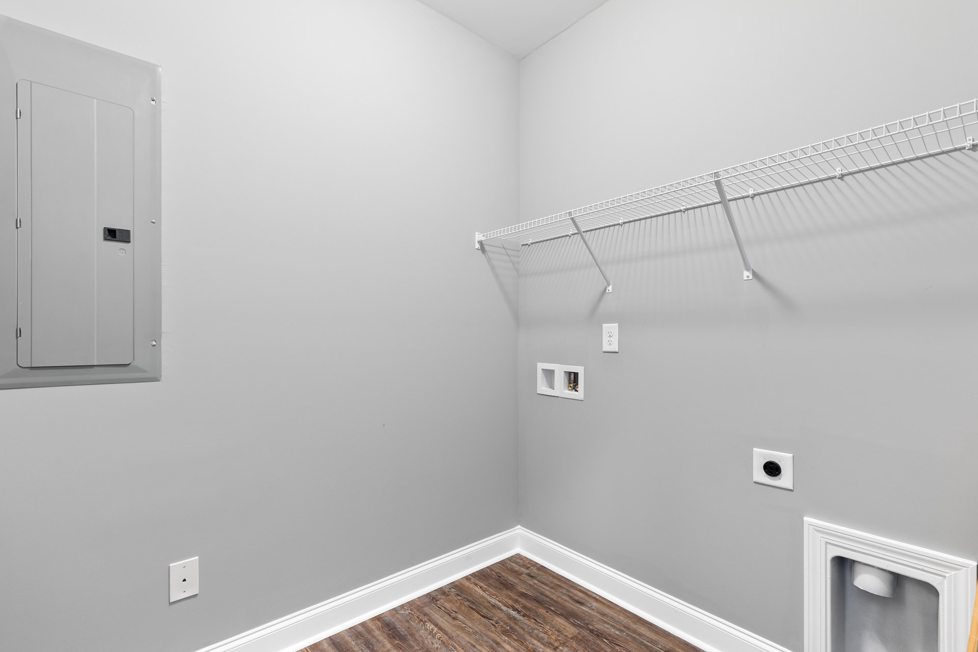 White built-in shelf against a plaster wall in a bathroom, with a white wall outlet and a white door featuring a square cutout.