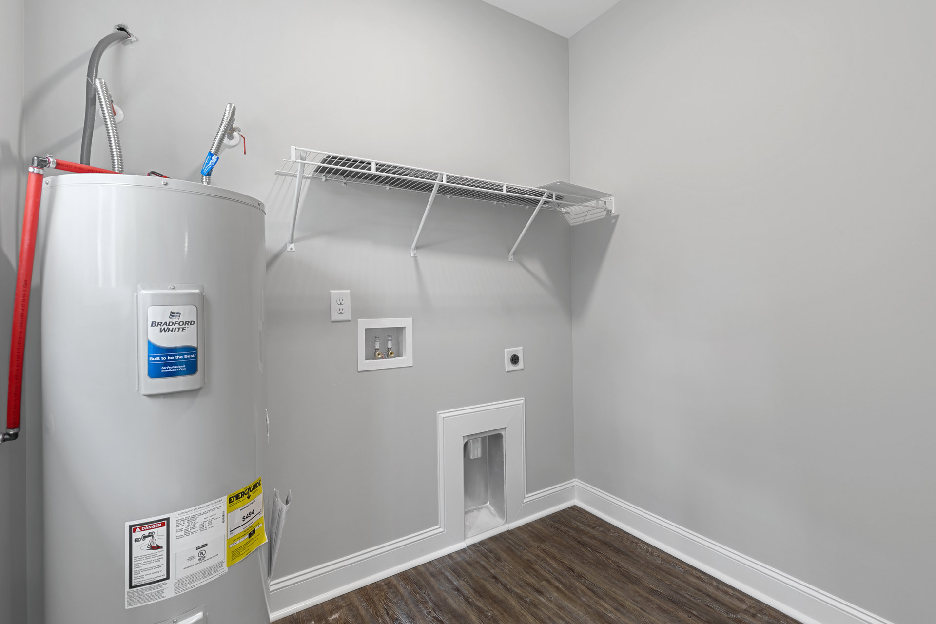 Bathroom with white plaster walls, built-in white shelf, silver faucet, fire extinguisher, and household supplies including a labeled container and hose.