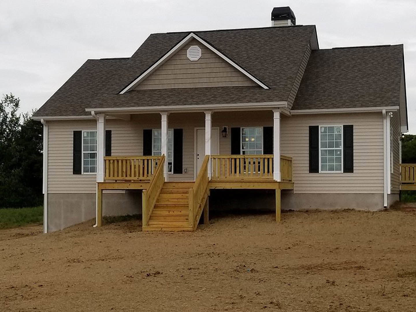 White siding house with black shuttered window, wooden porch and deck, wooden stairs leading from dirt ground, exterior wall vent visible