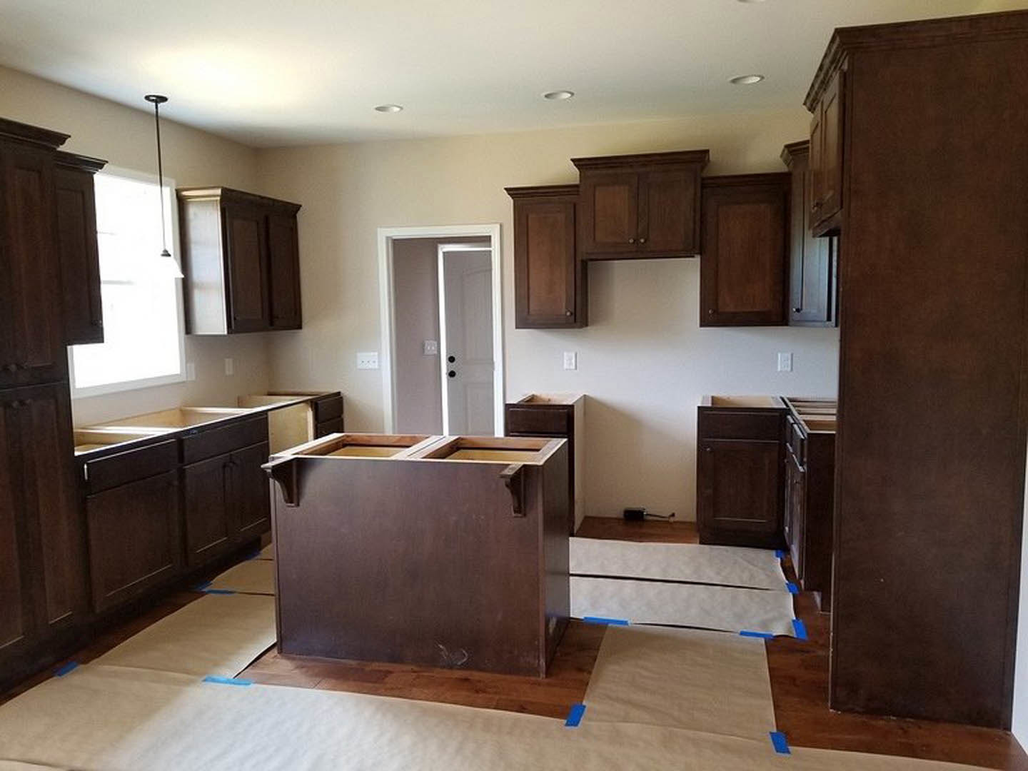 Kitchen featuring dark wood cabinets, white ceiling, light-colored countertops, and natural light streaming through a window