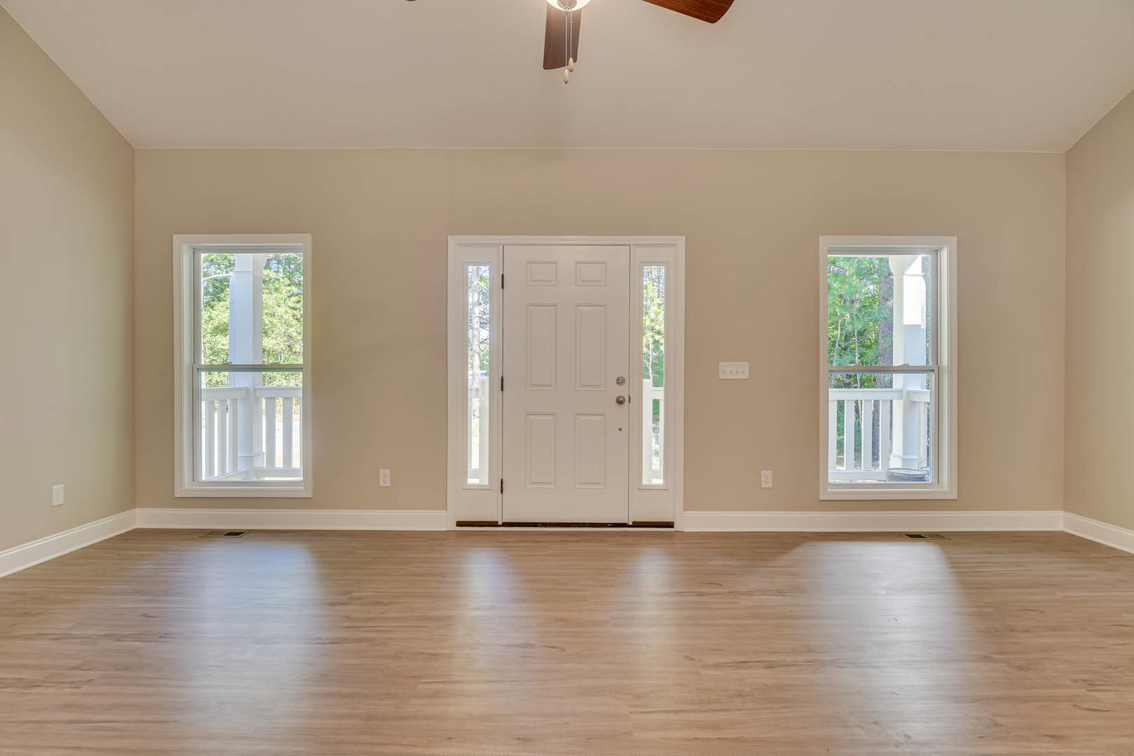 Wood flooring with light reflection, white door featuring glass panels, ceiling fan with light fixture, window framed by white railing, trees visible outside