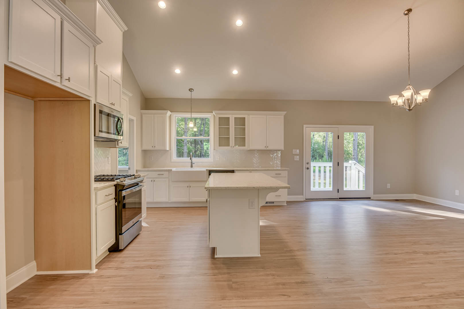 White kitchen and dining room featuring white cabinets, a white kitchen island with pendant light, wood flooring, glass-paneled double doors, built-in microwave with glass door