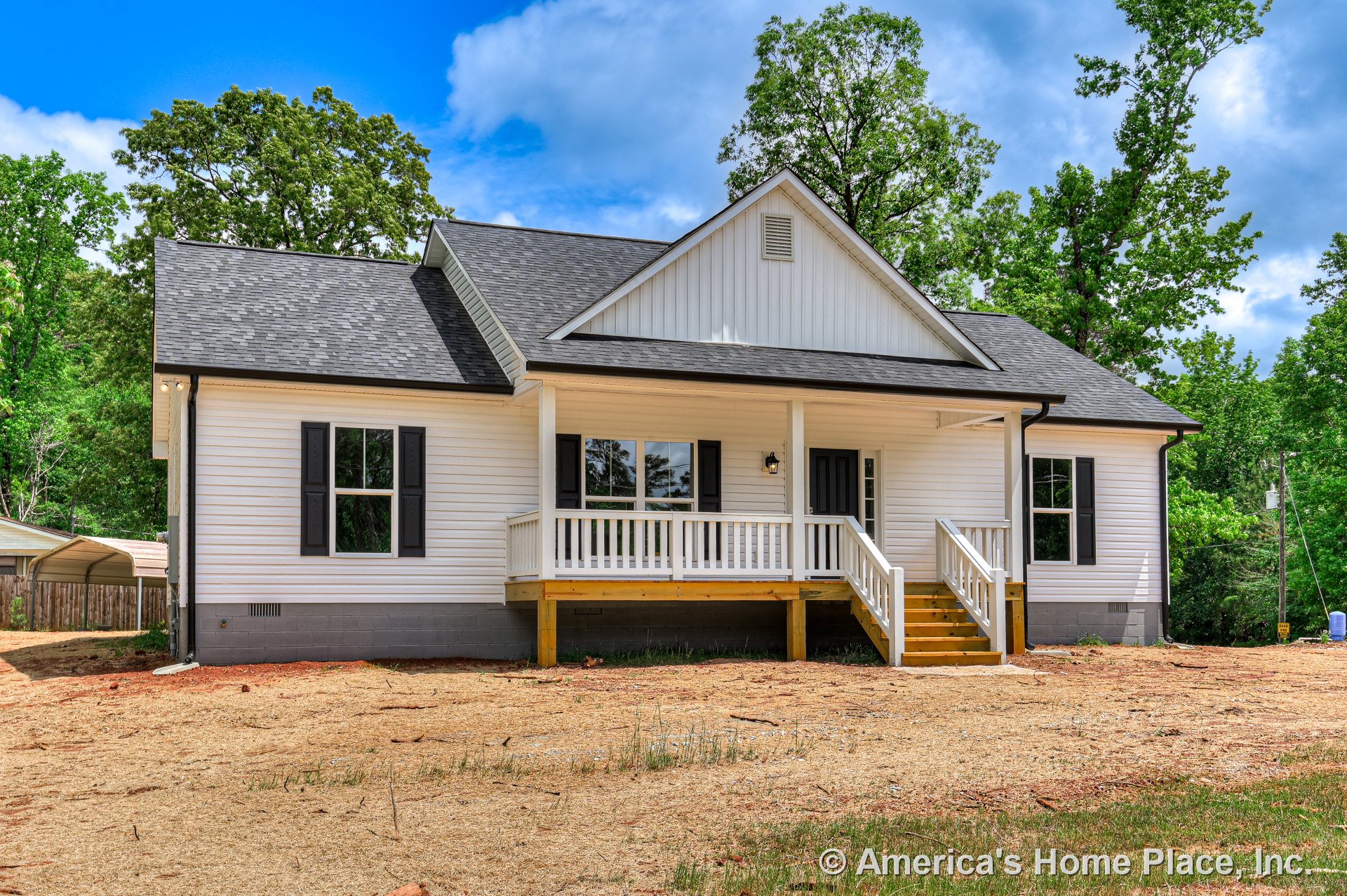 Covered front porch with white railings and wooden steps, black front door, white siding exterior, black shutters, gabled roof, double-hung windows, and exterior lighting fixture.