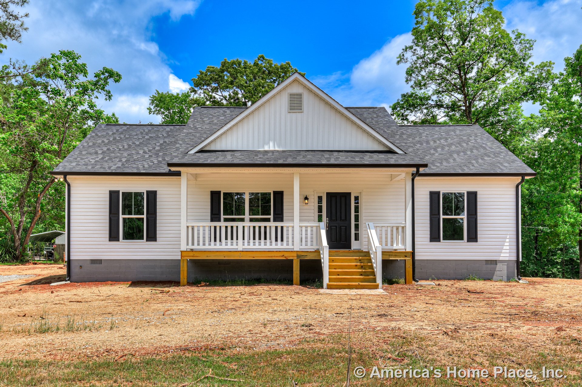 Covered front porch with white railings, black front door, white horizontal siding, black window shutters, gray shingle roof, wooden steps, double front windows, and exterior light