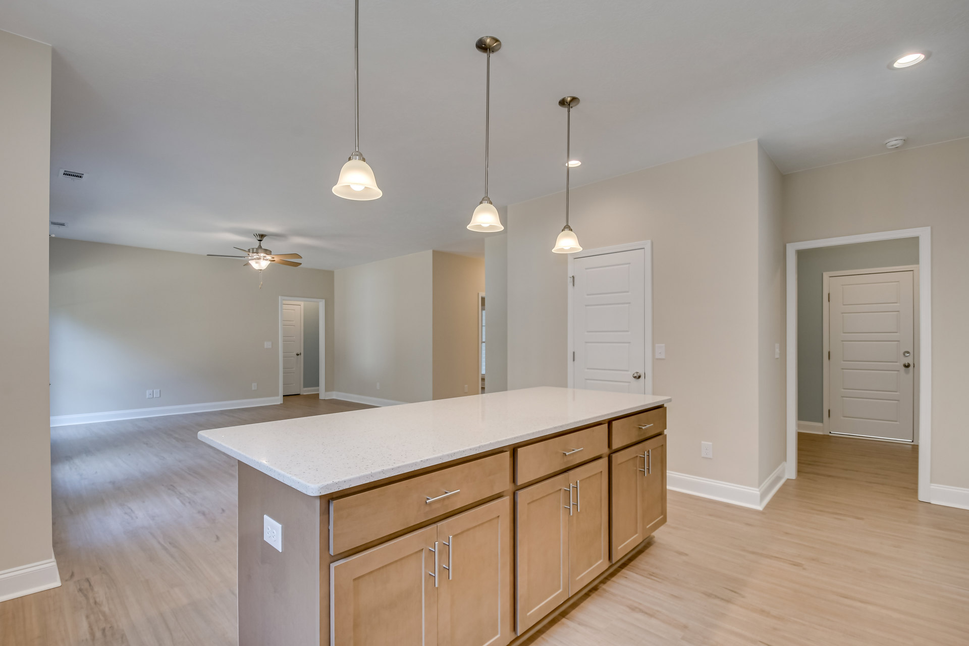 Kitchen with tile flooring, central island featuring drawers and cabinets, white doors with silver hardware, ceiling light fixture, and sleek metal pole.