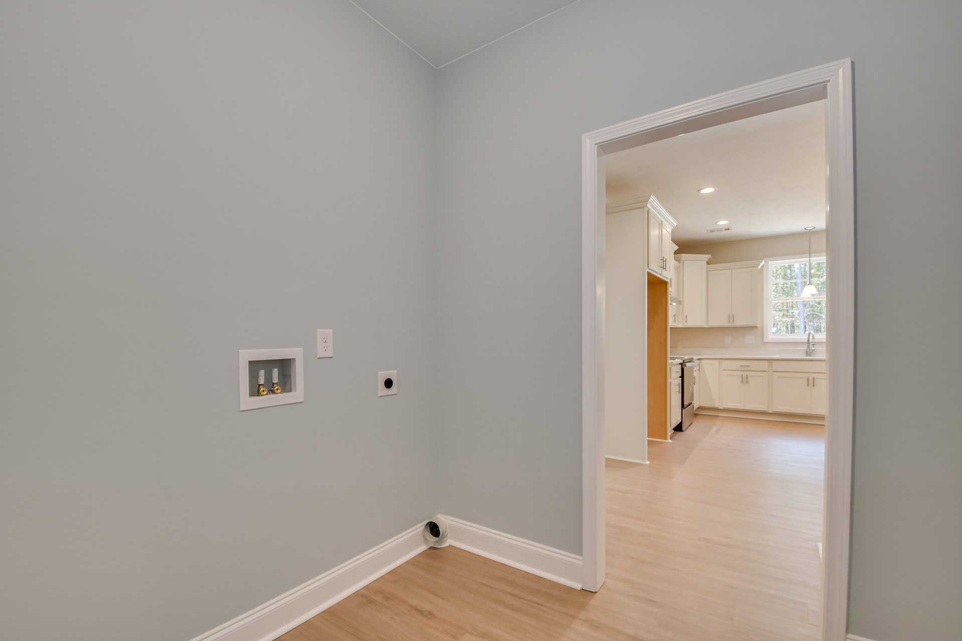 Light wood flooring, white paneled door, smooth white walls, large window with simple trim, ceiling light fixture