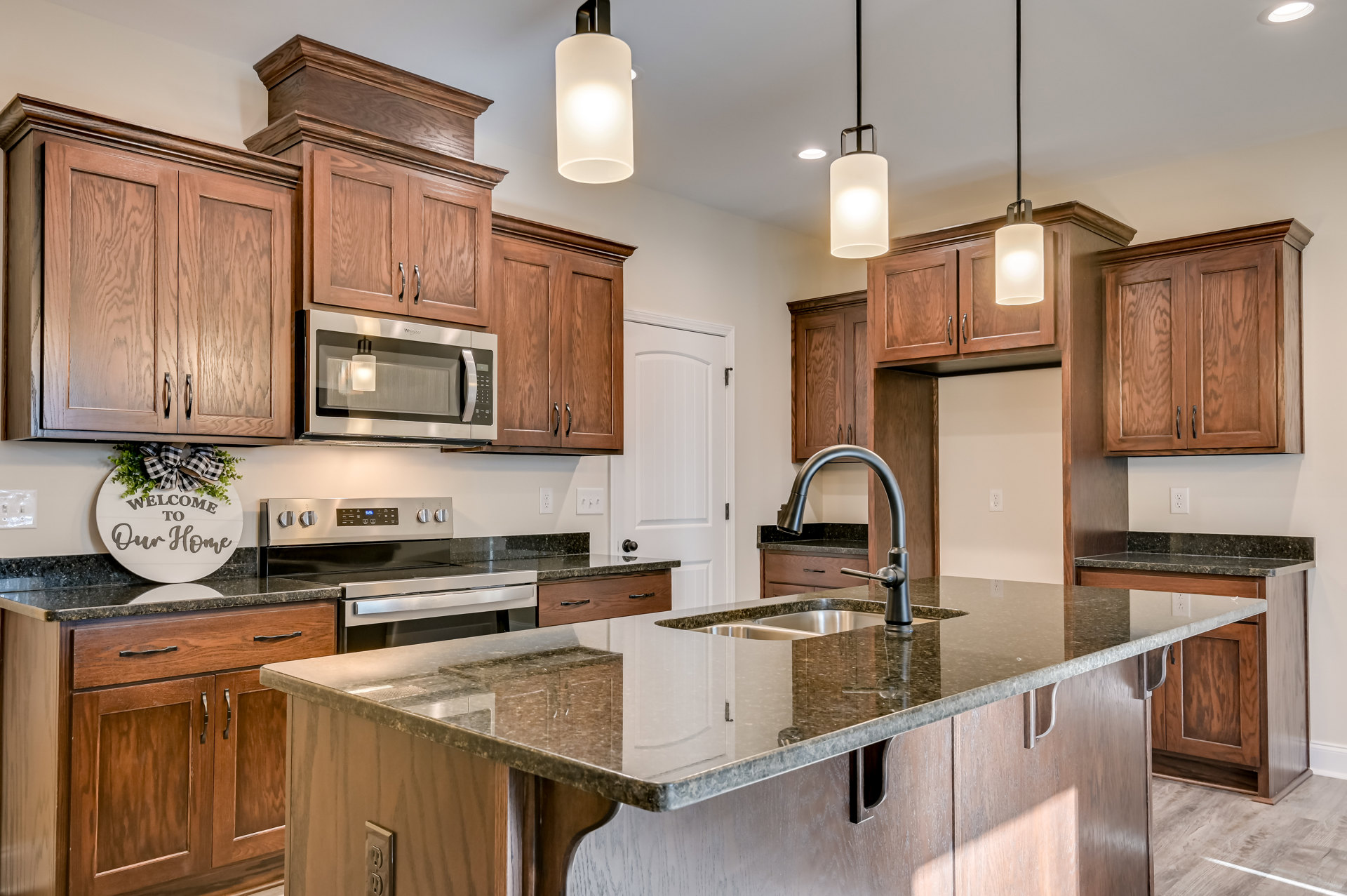 Modern kitchen featuring white cabinetry, stainless steel sink and stove, quartz countertop, built-in microwave, and under-cabinet lighting