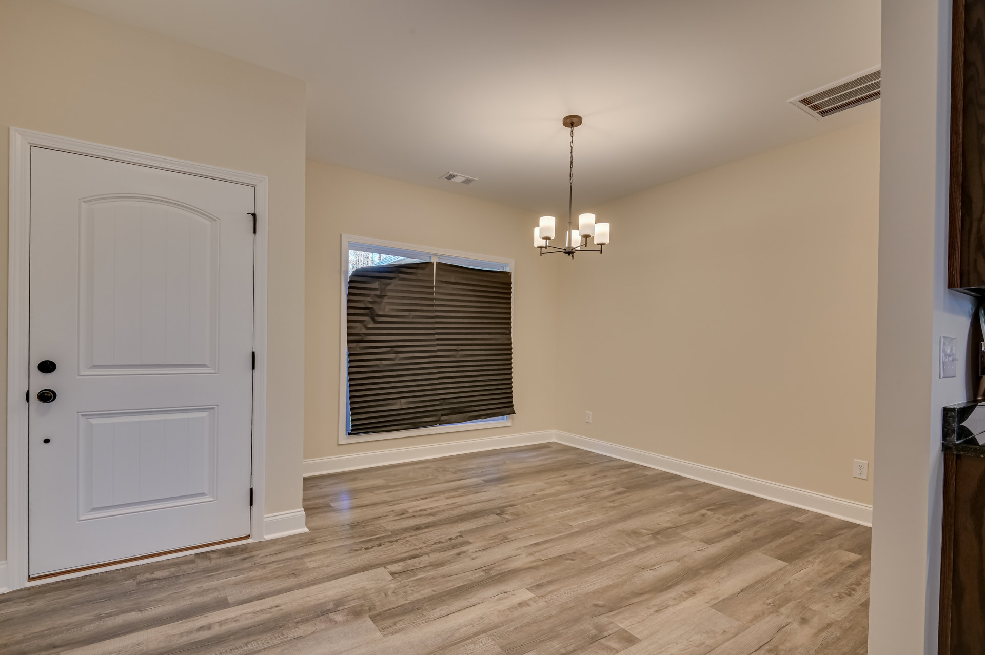 Wood floor room with white door featuring black knobs, black window blind, and ceiling chain.