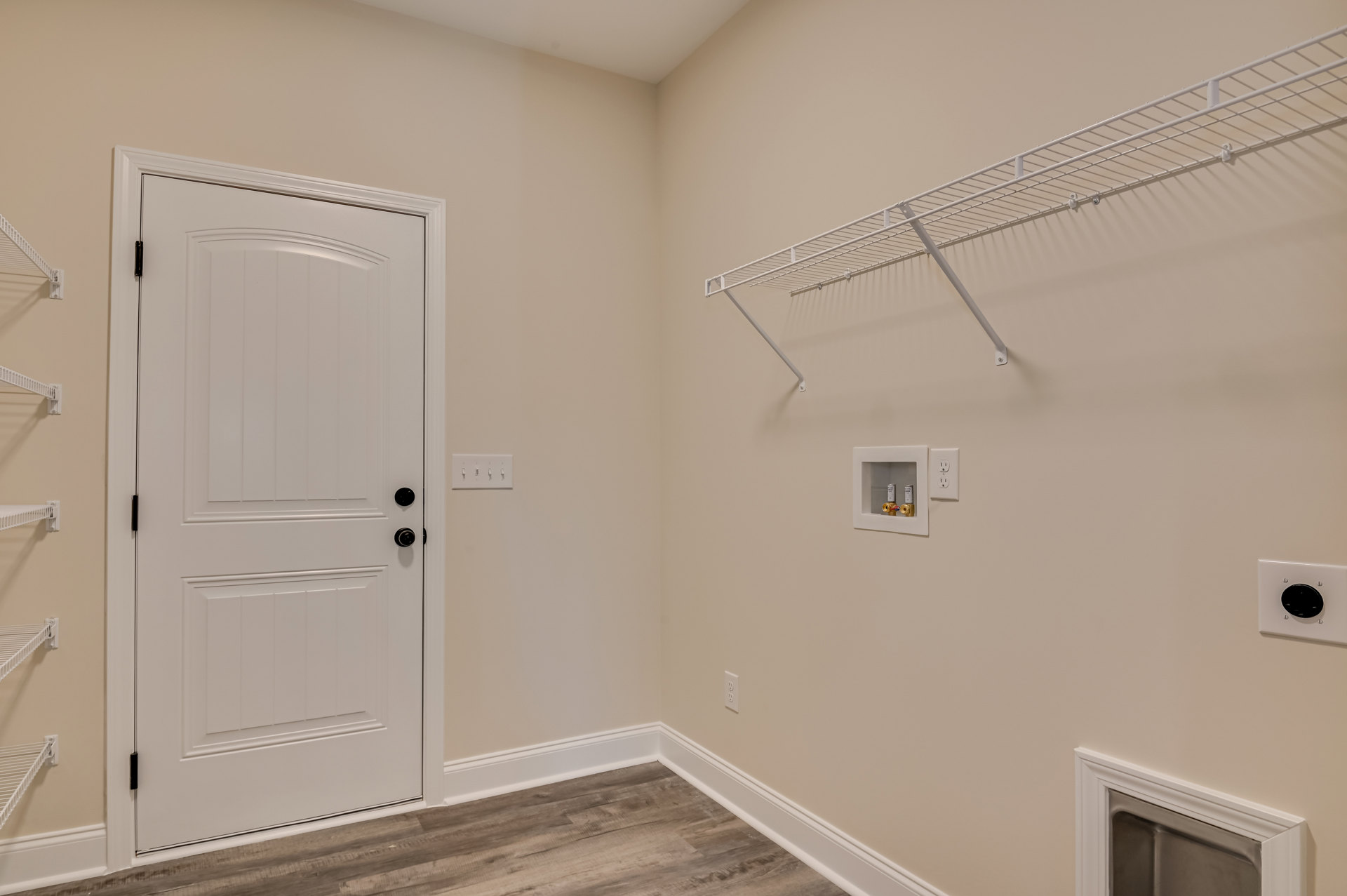 White bathroom with plaster walls, white door featuring black knobs, wall-mounted metal shelf, glass shower window, and ceiling molding.