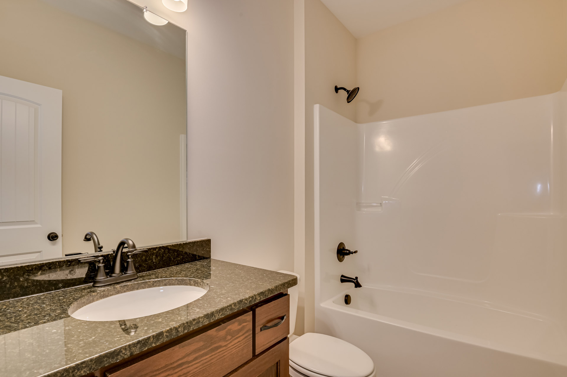 Modern bathroom with white ceramic sink, chrome faucet, glass-enclosed shower, light gray tile walls, and a white toilet