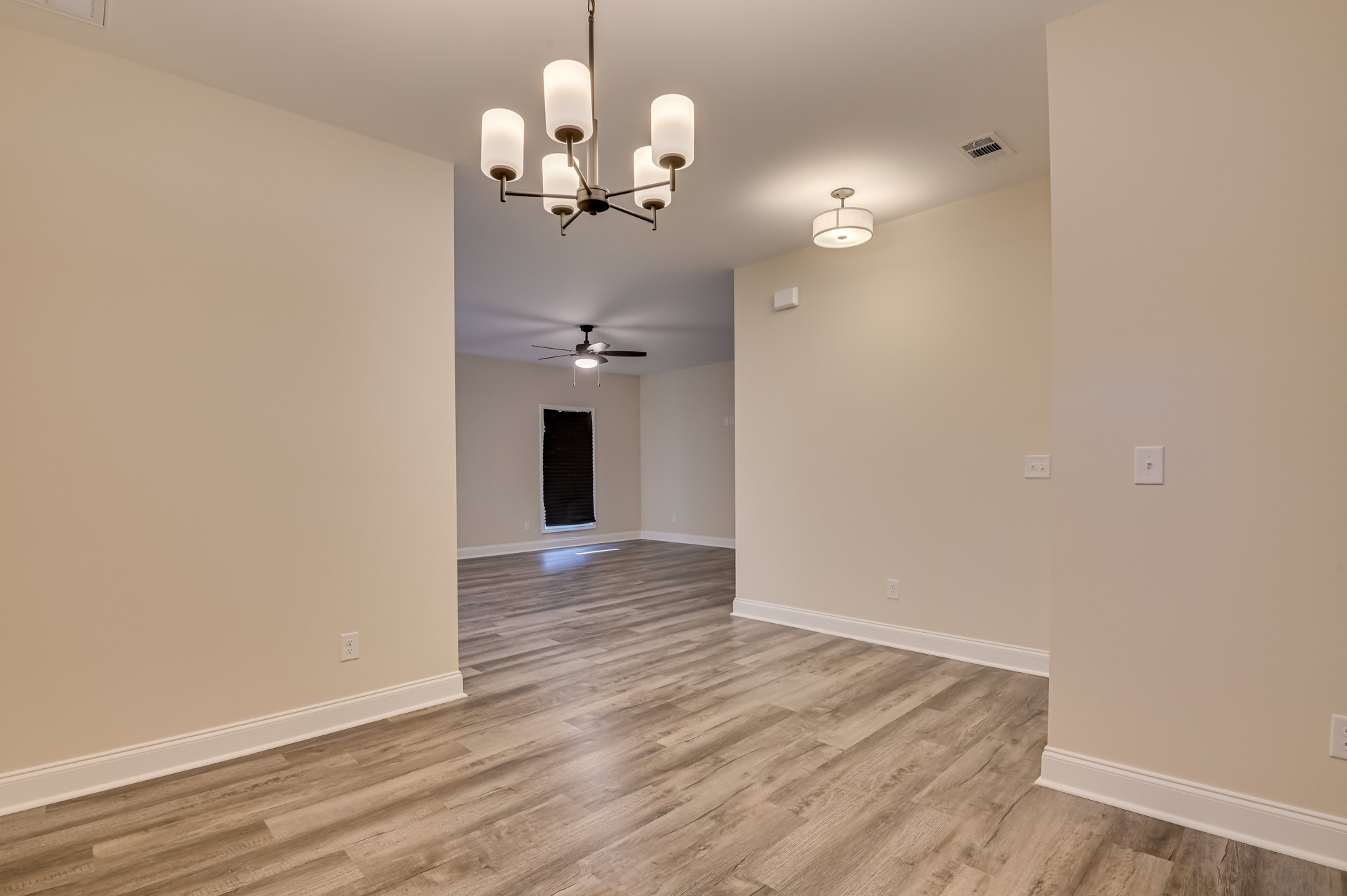 Wood flooring in a room with white plaster walls, ceiling fan, and modern light fixture with white shade