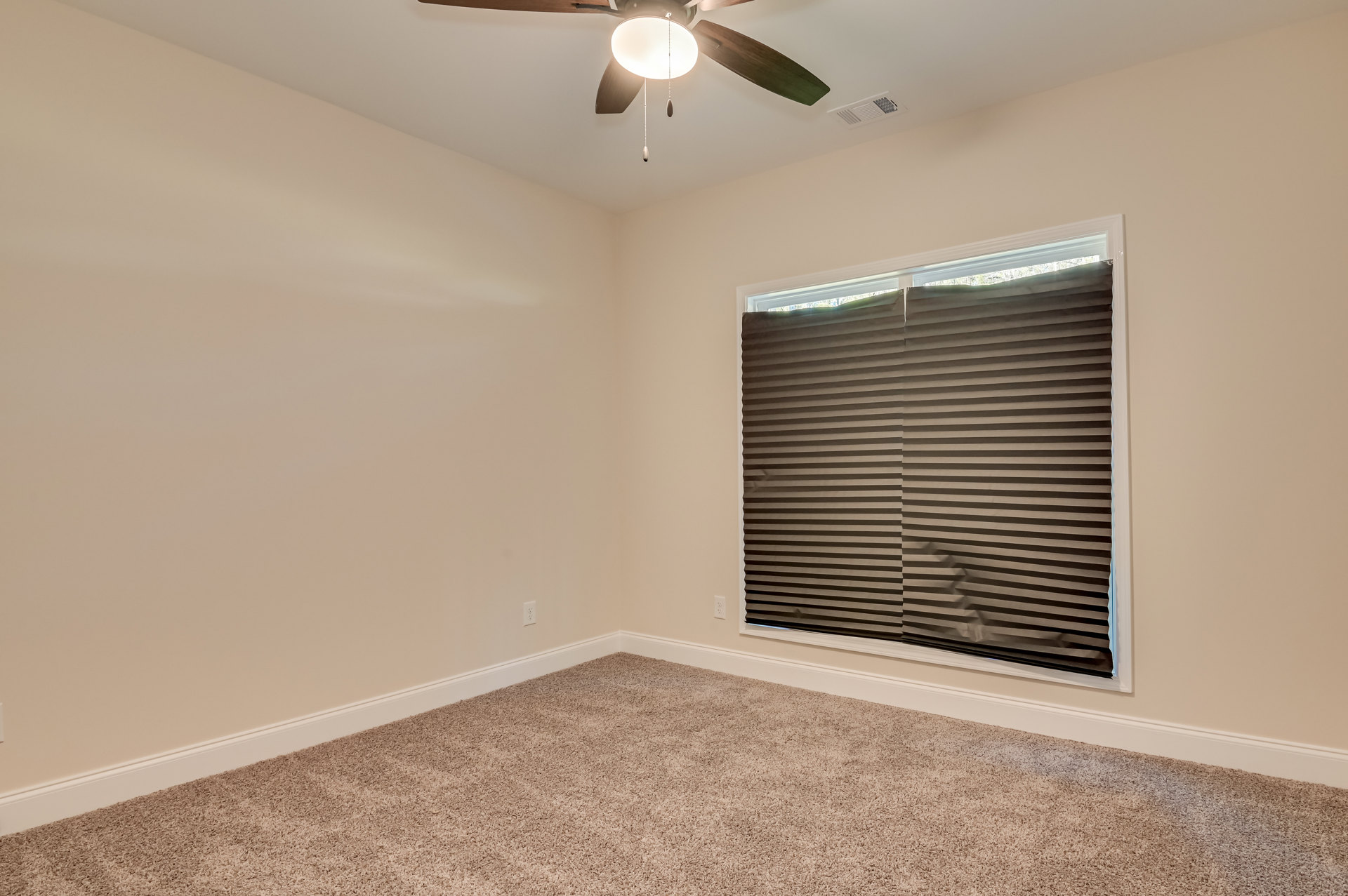 Carpeted room with white walls, ceiling fan with light fixture and pull chain, window with horizontal blinds