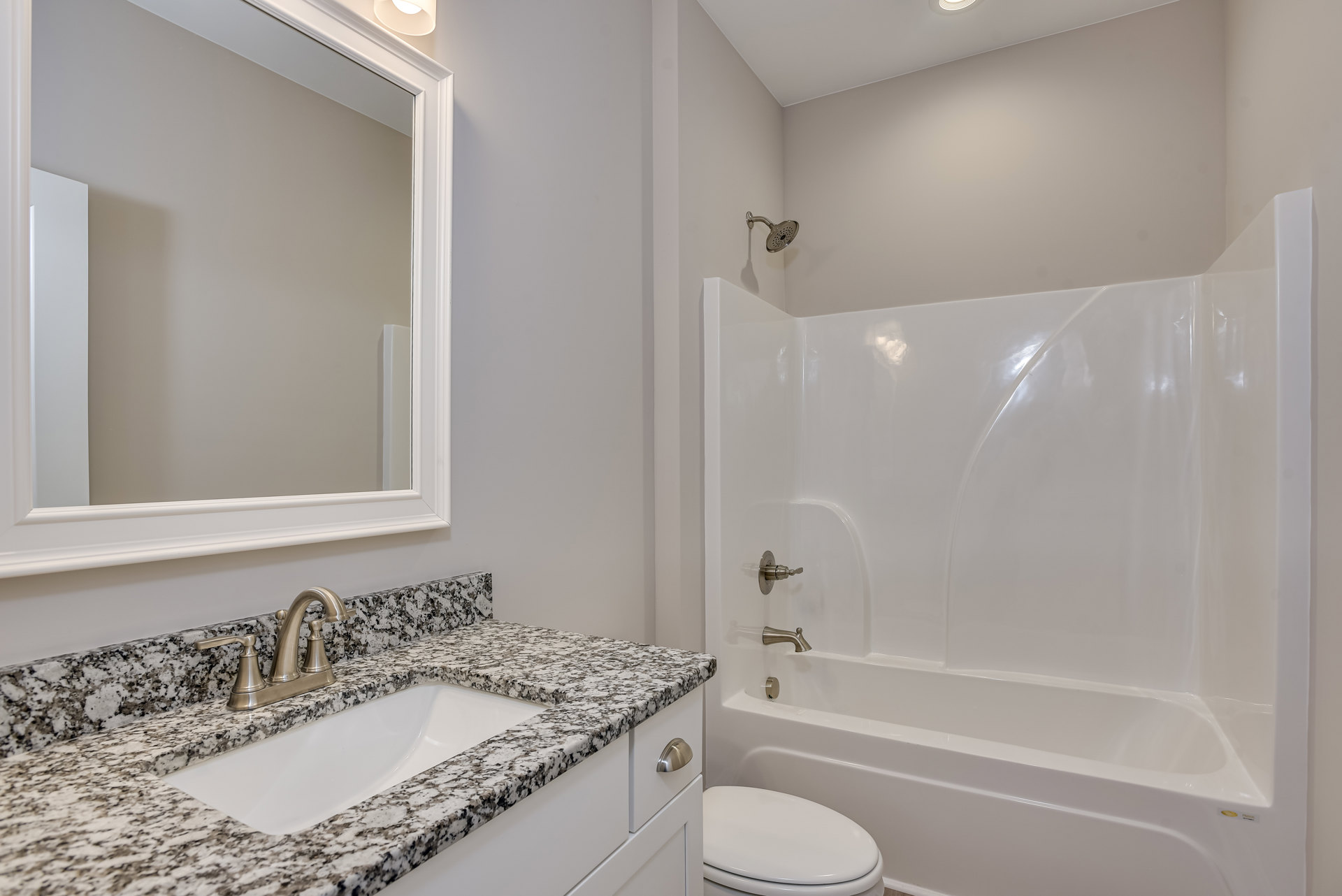 Bathroom with white toilet, marble countertop sink, chrome faucet, wall-mounted mirror, and tiled walls
