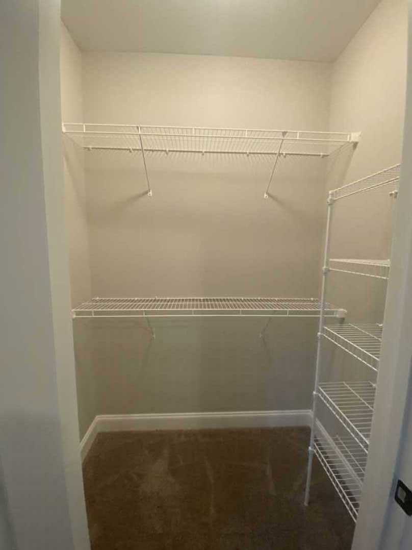 Walk-in closet with built-in white shelves and gray tile flooring