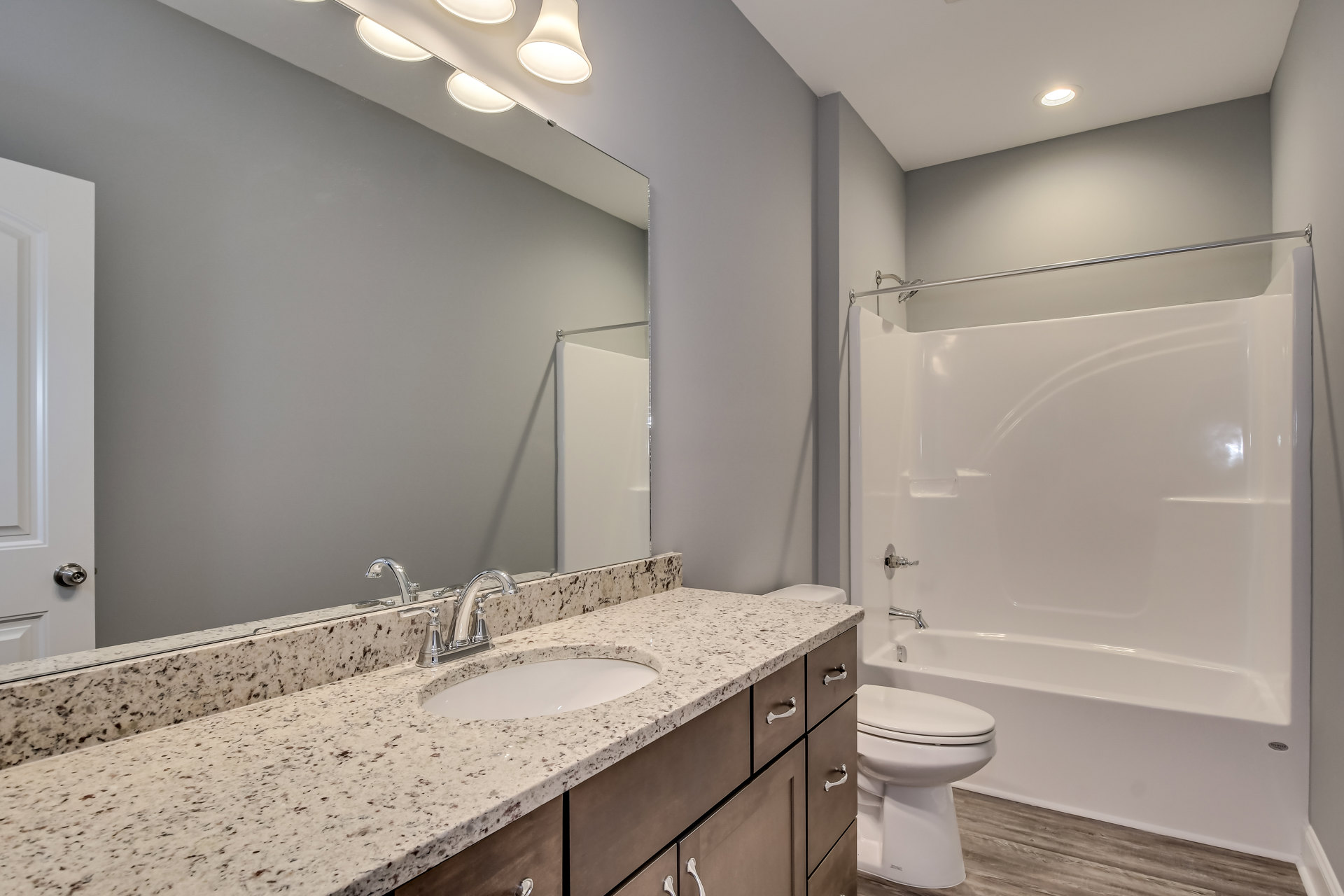 Bathroom with white porcelain sink and chrome faucet, white toilet with closed lid, light-colored tile walls and floor, minimal decor