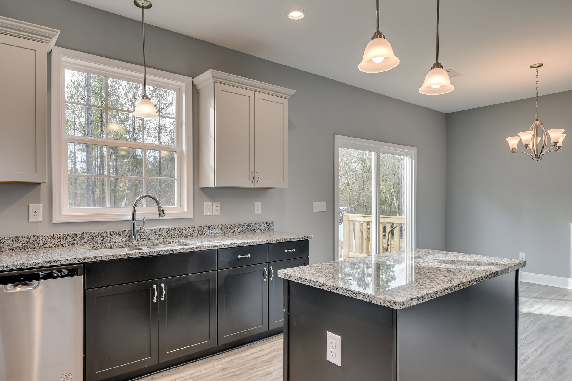 Granite countertops, white cabinetry, stainless steel sink, ceiling light fixture, white electrical outlet, metal pole with white base