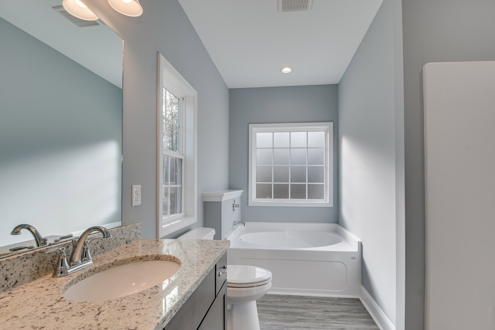 White bathroom with tiled walls, frosted glass window, modern sink and faucet, white toilet with closed lid