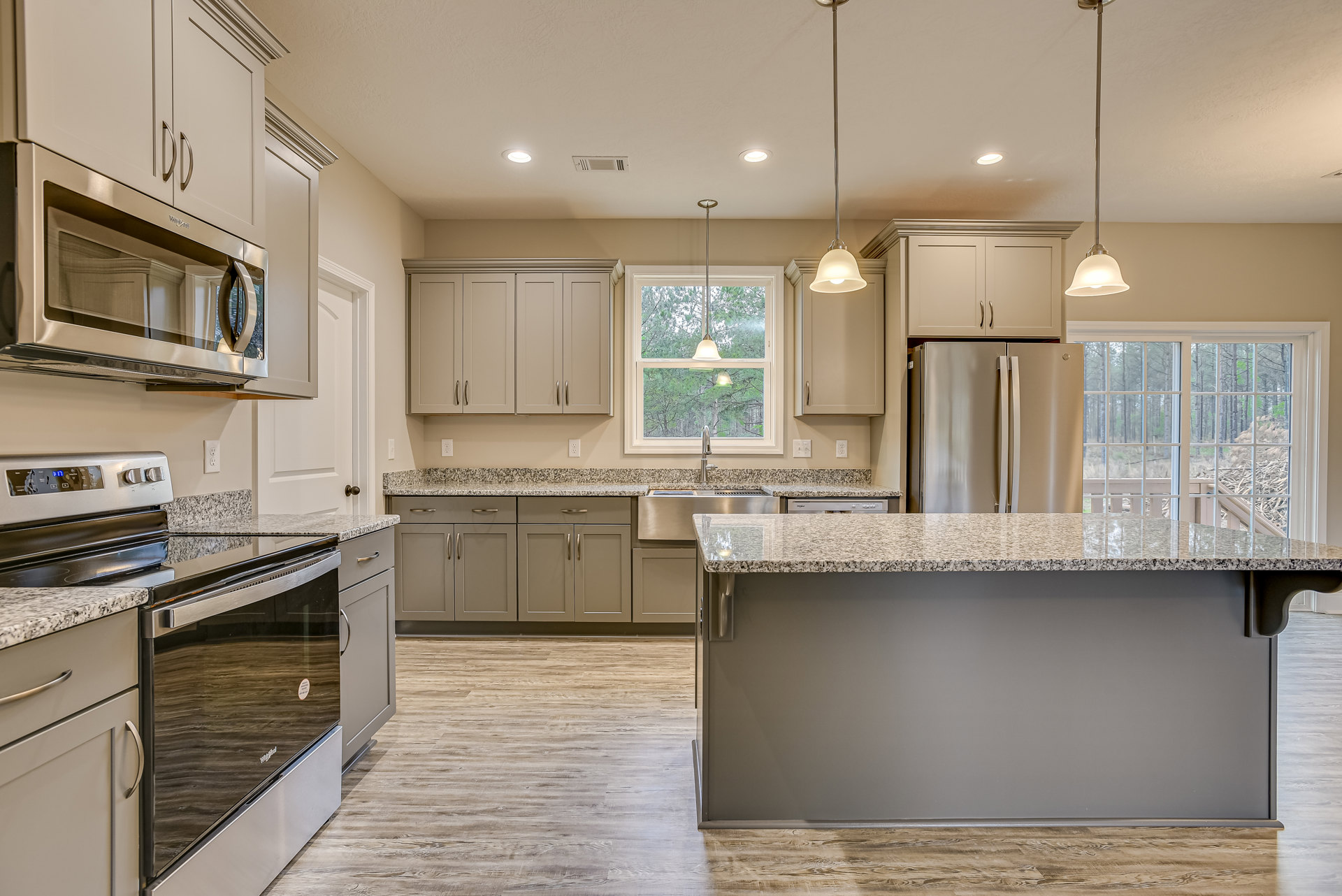 Granite countertops, stainless steel refrigerator, white cabinetry, built-in microwave, and modern pendant lighting in a contemporary kitchen