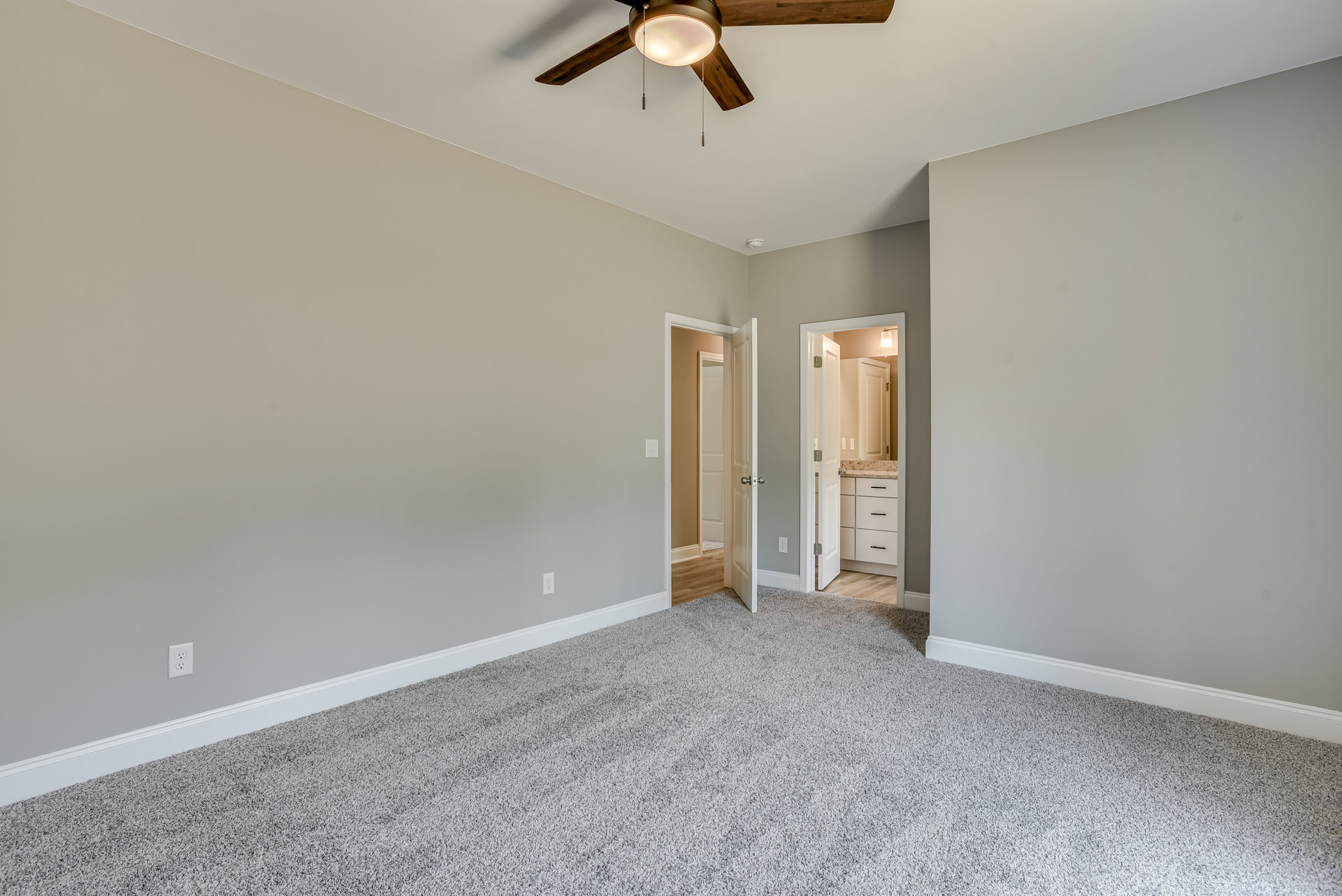 Bedroom with white carpet, ceiling fan with light fixture, wall-mounted mirror, white door with silver knob, marble countertop, and white drawer.